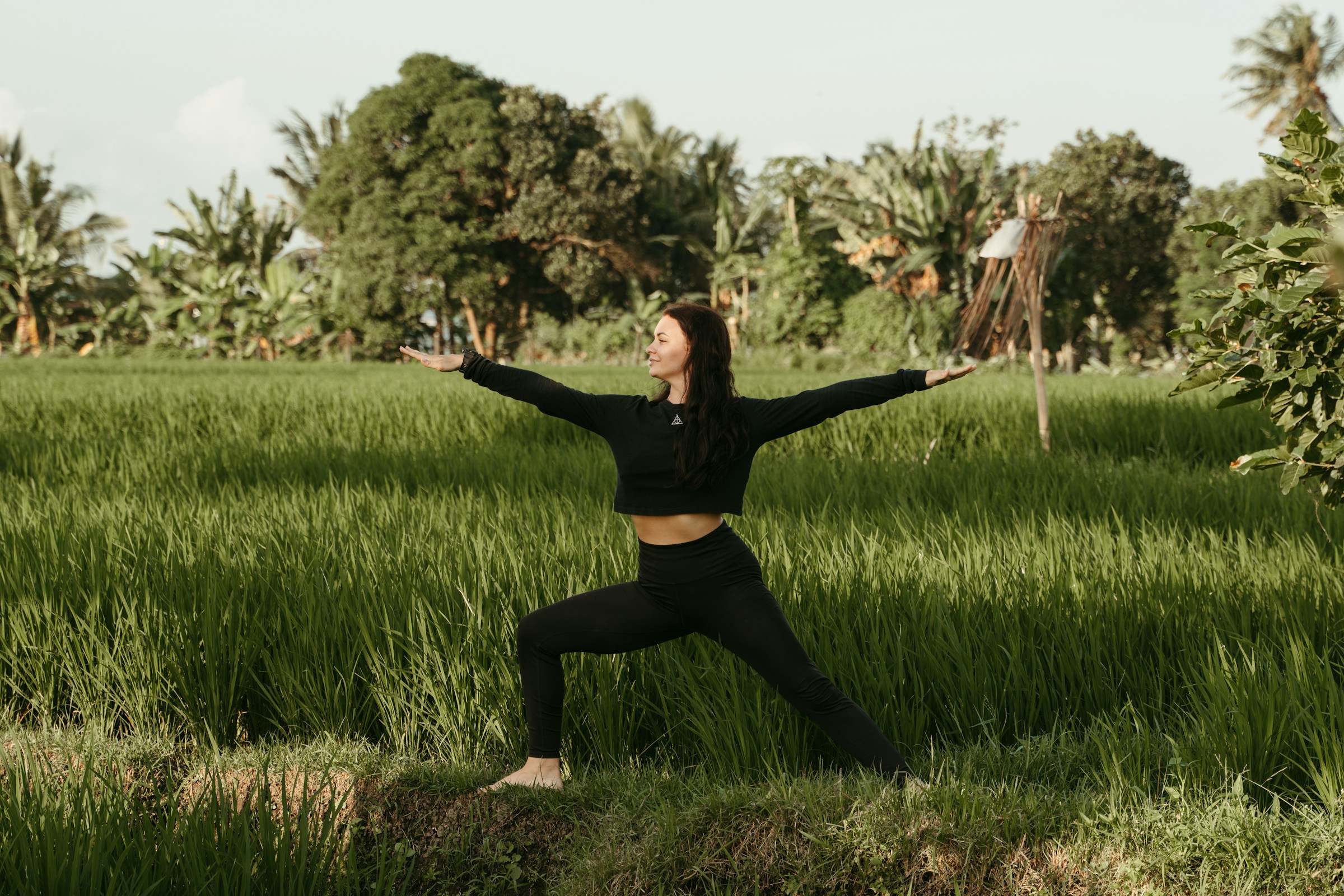 Woman dressed in black practicing yoga in nature in Bali