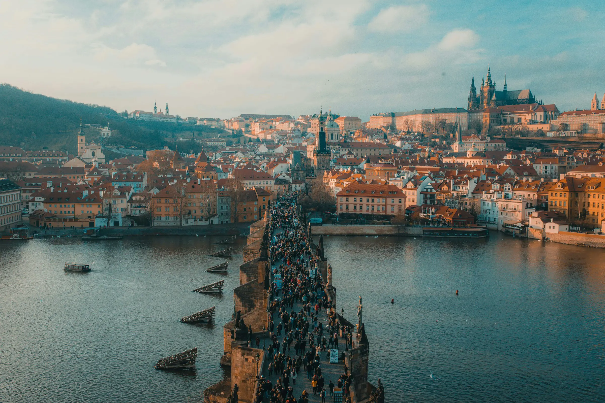 The Charles Bridge in Prague over a river meets the city with a castle in the background