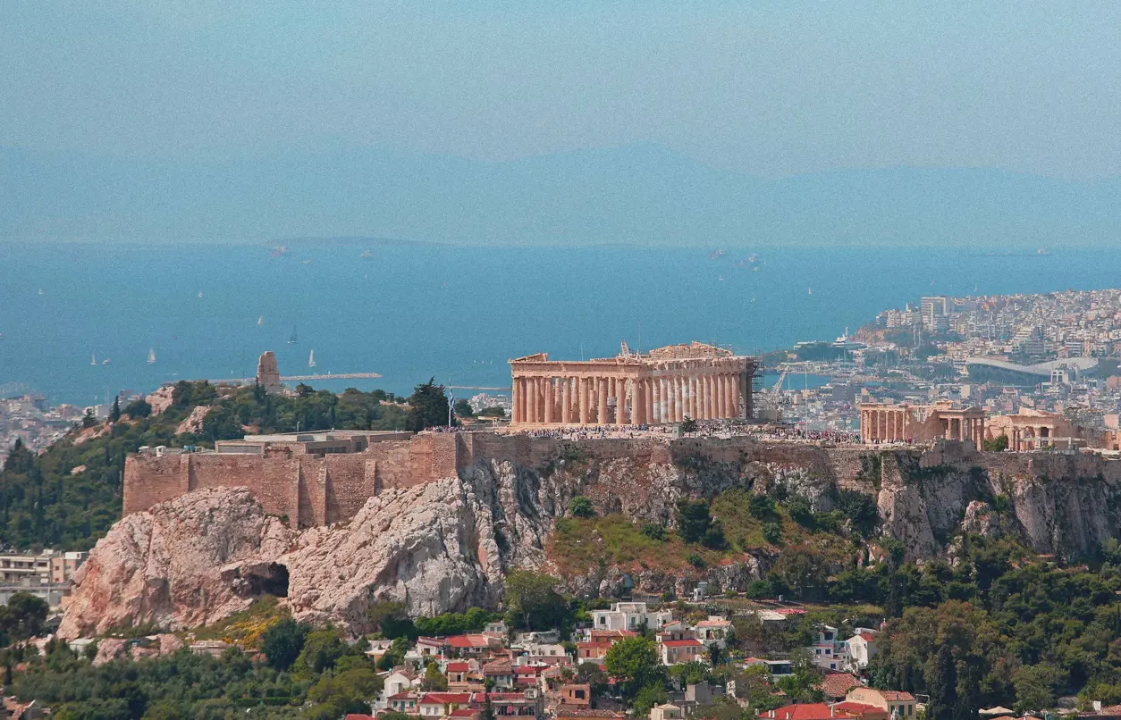 Utsikt över Akropolis i Aten med Parthenontemplet på klippan och Medelhavet i bakgrunden. Historisk sevärdhet och populärt resmål i Grekland.