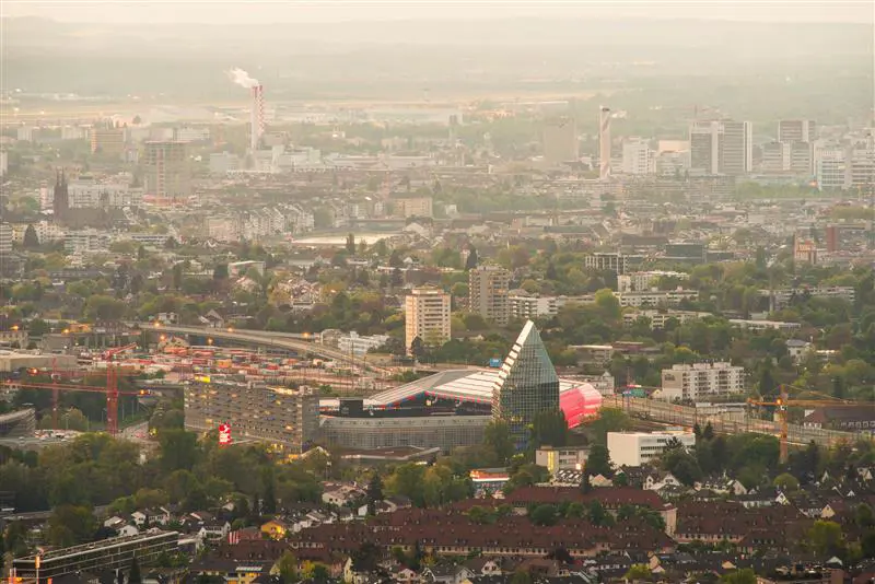 Luftfoto av en by med moderne bygninger og infrastruktur, tåkete lys over skyline.