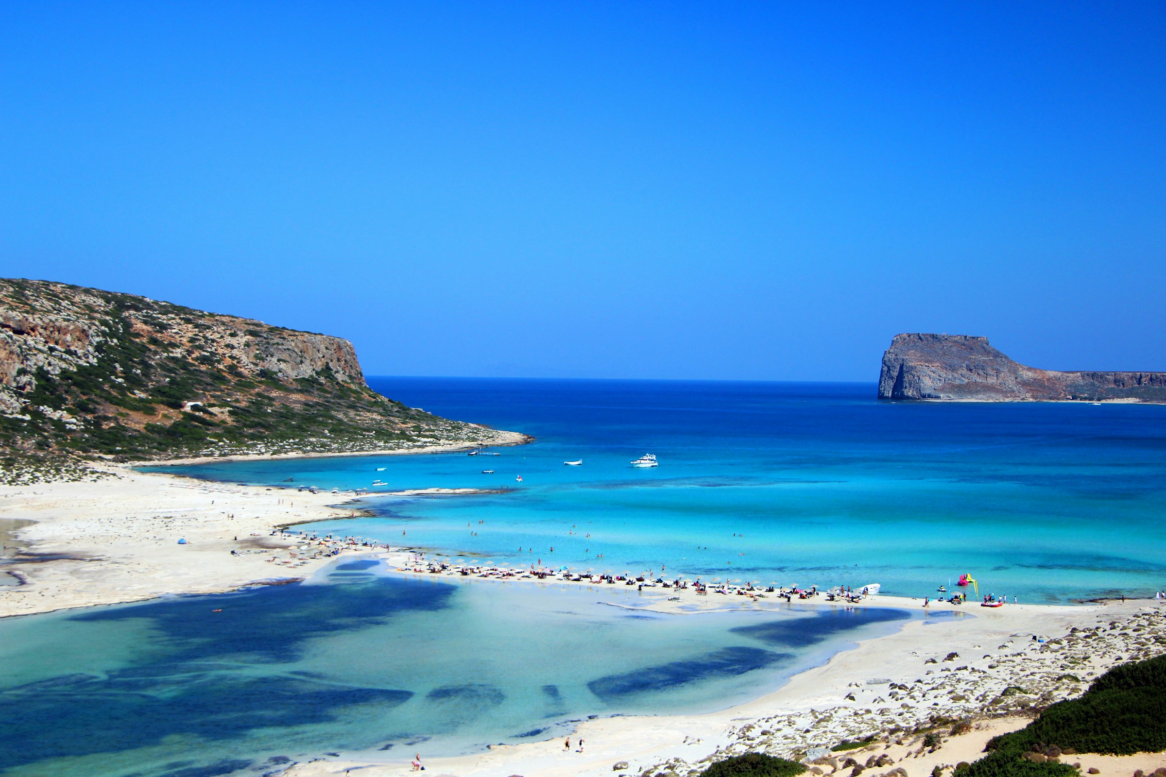 Pristine Balos Beach in Crete, Greece with turquoise waters, sandy shores, and a distant rocky island under a clear blue sky
