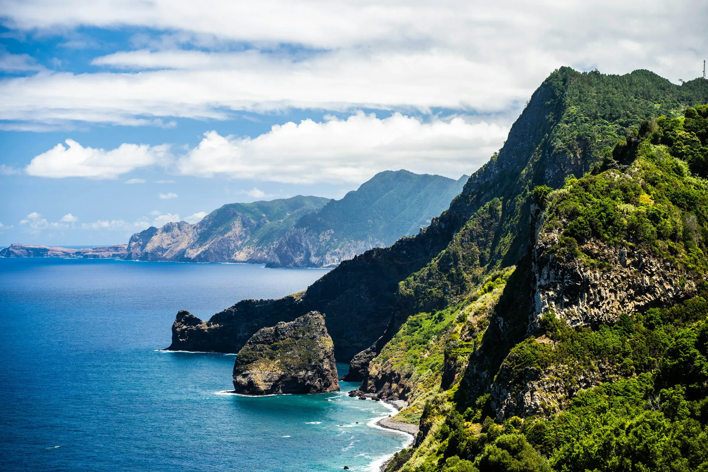 Coast with high cliffs meeting the sea with sky and clouds in the background