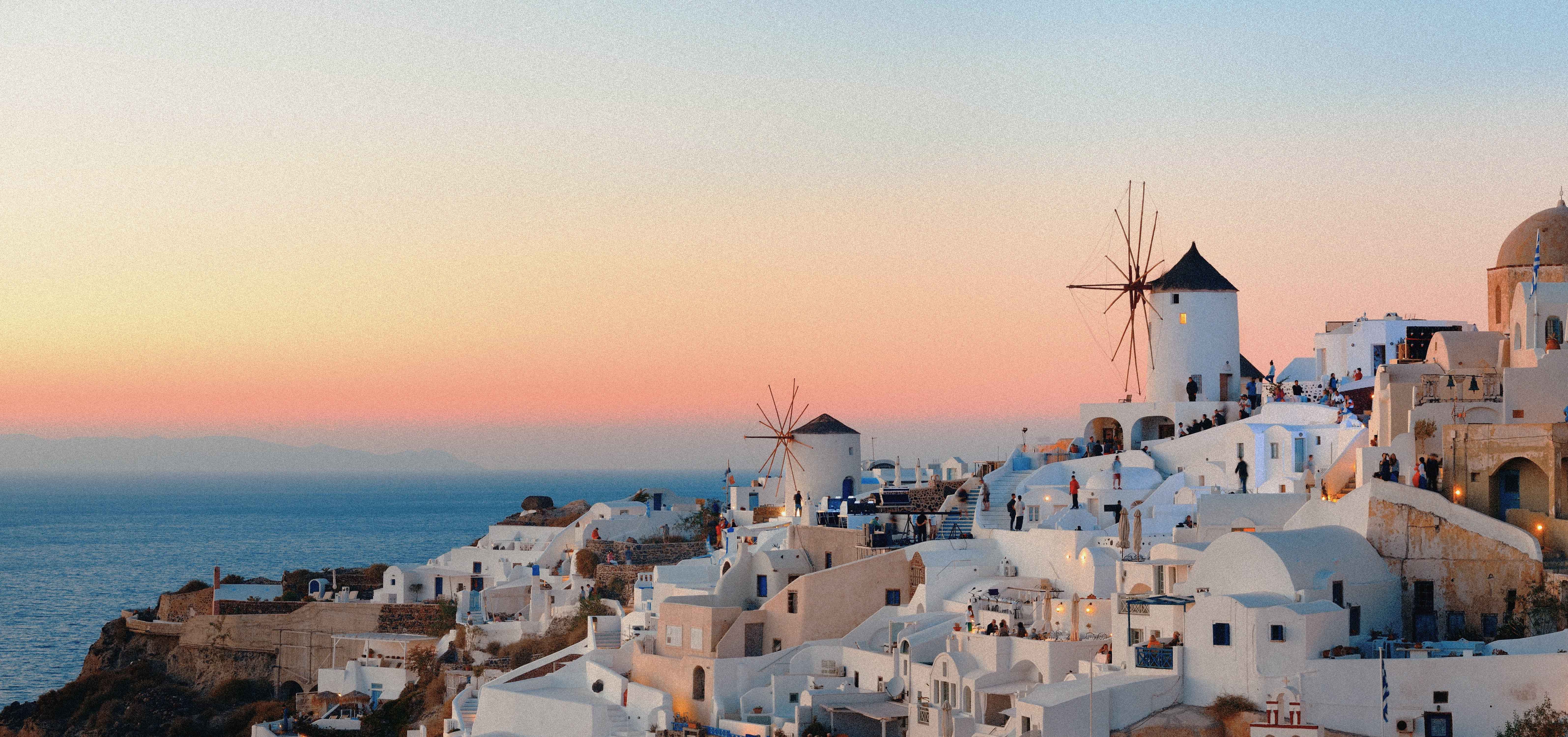 Hvitkalkede hus og klassiske vindmøller i Oia, Santorini under solnedgang. Romantisk utsikt over Egeerhavet i Hellas.