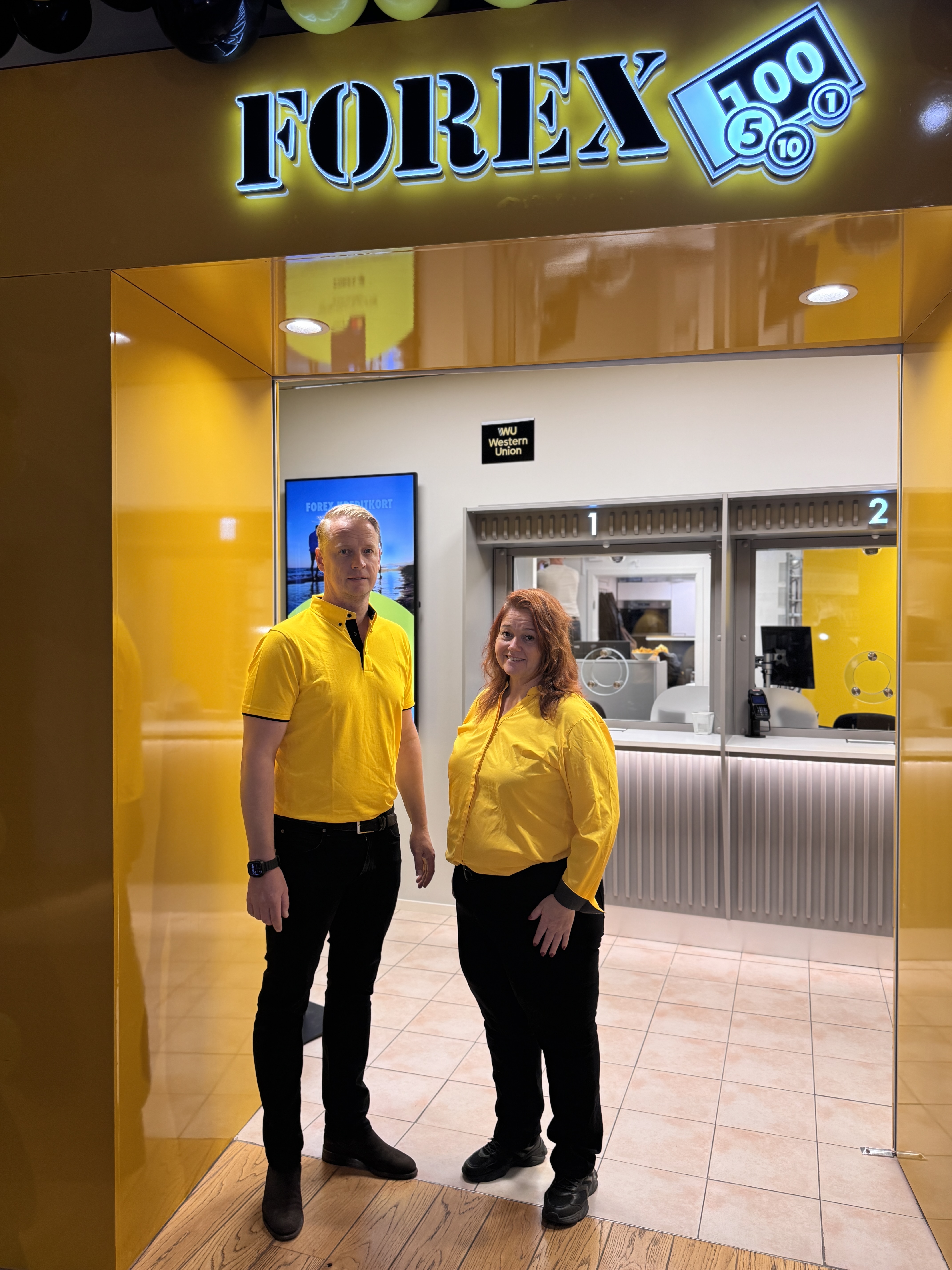 Två personer i gula skjortor står framför en nyöppnad FOREX-butik i Triangeln, Malmö.