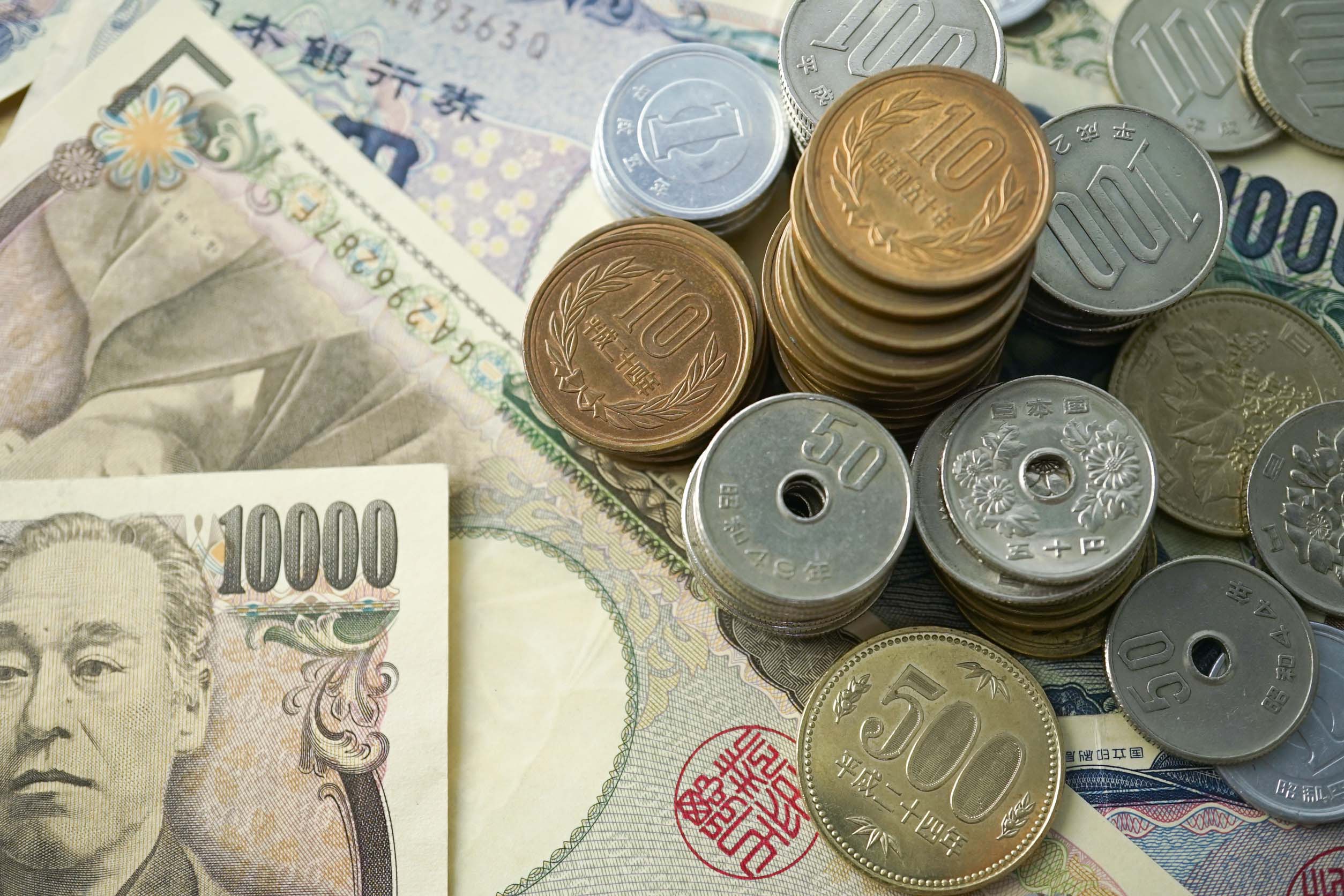 Japanese coins and banknotes, including the 10,000 yen banknote, arranged on a surface.