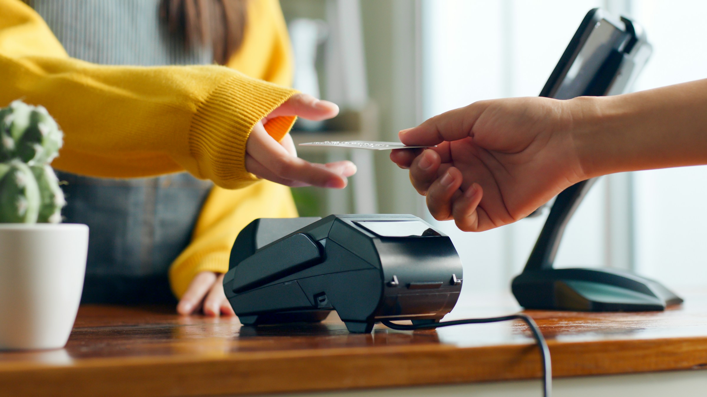 Customer making a contactless payment with a credit card at a point-of-sale terminal in a retail setting.