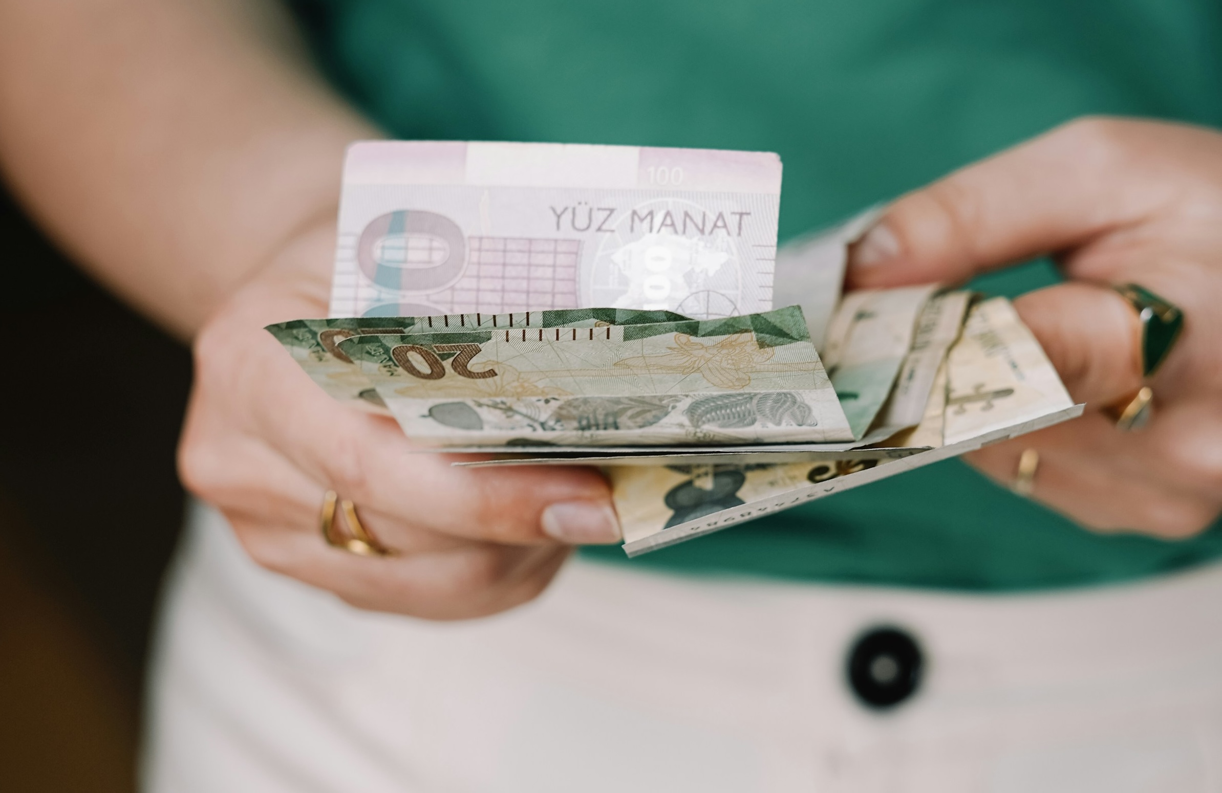 Person som holder en bunke med tyrkiske manat sedler.