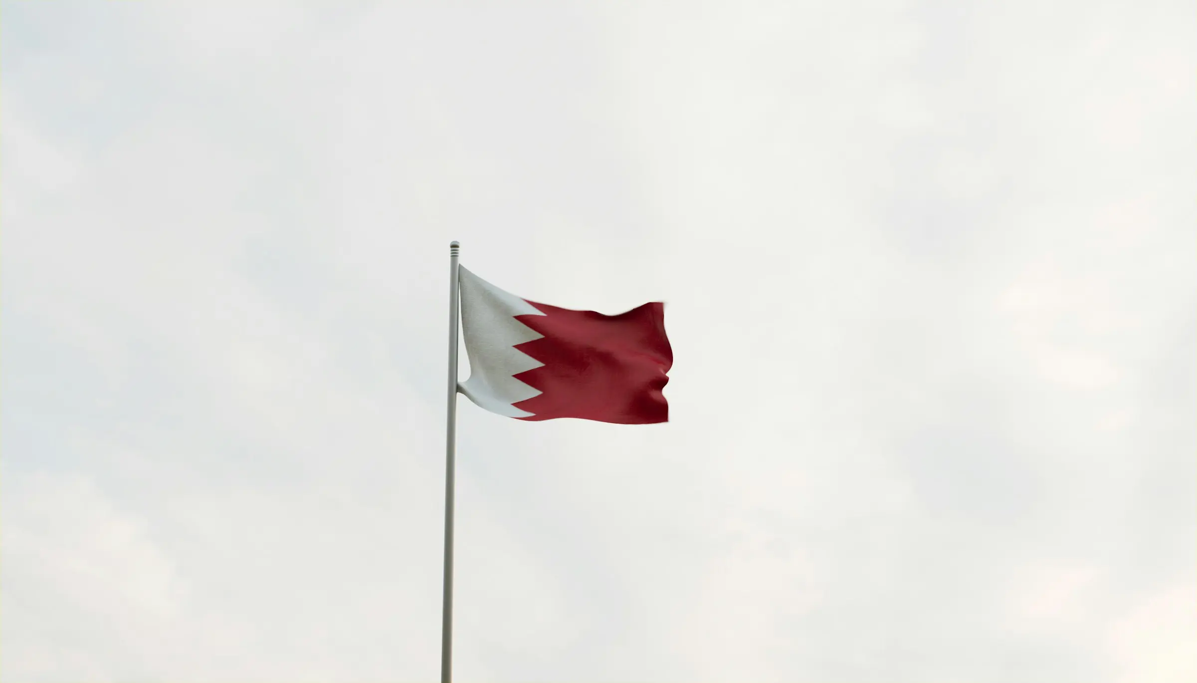 Bahrain national flag waving against a cloudy sky background.