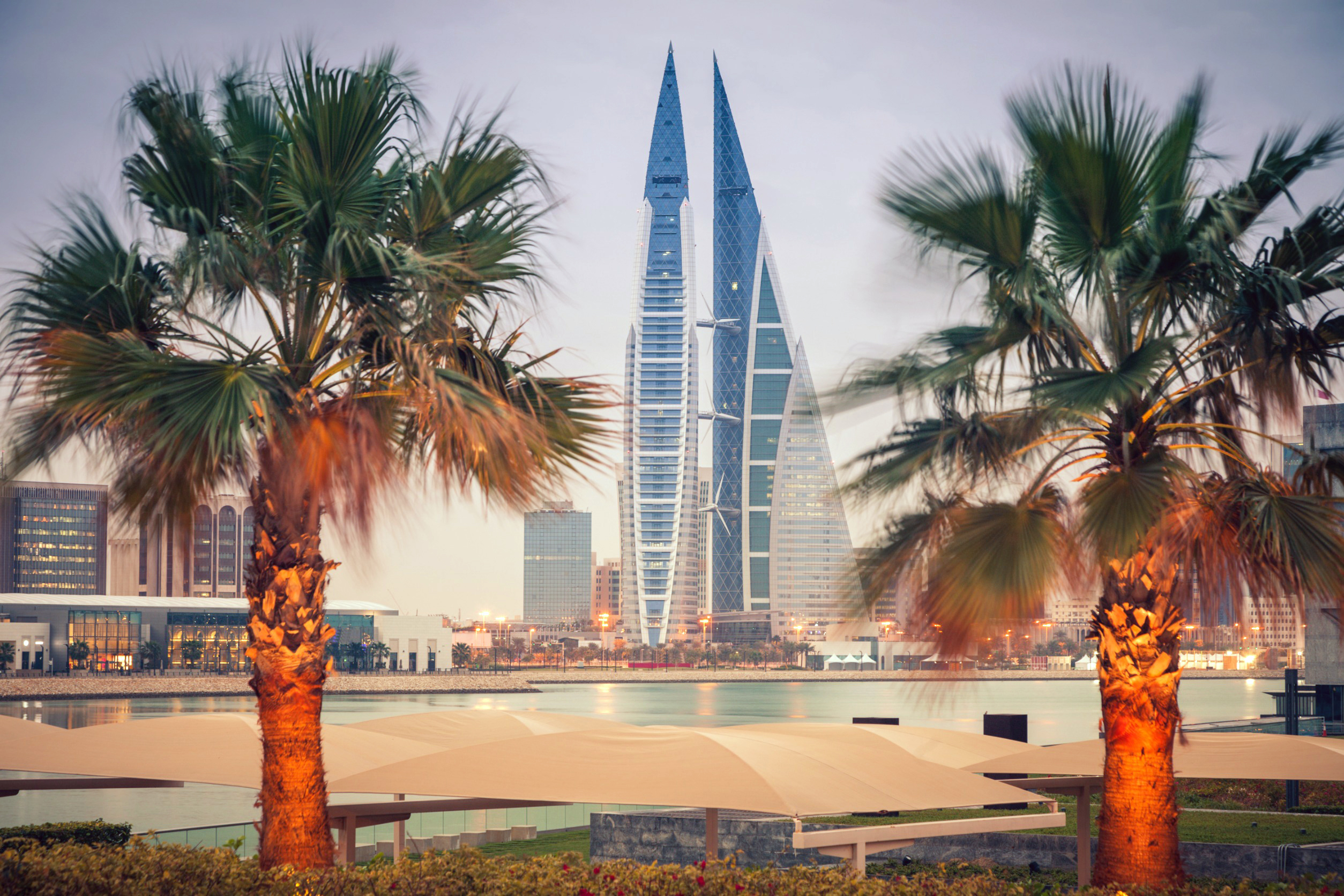 To moderne skyskrapere, Bahrain World Trade Center, omgitt av palmer i Manama, Bahrain