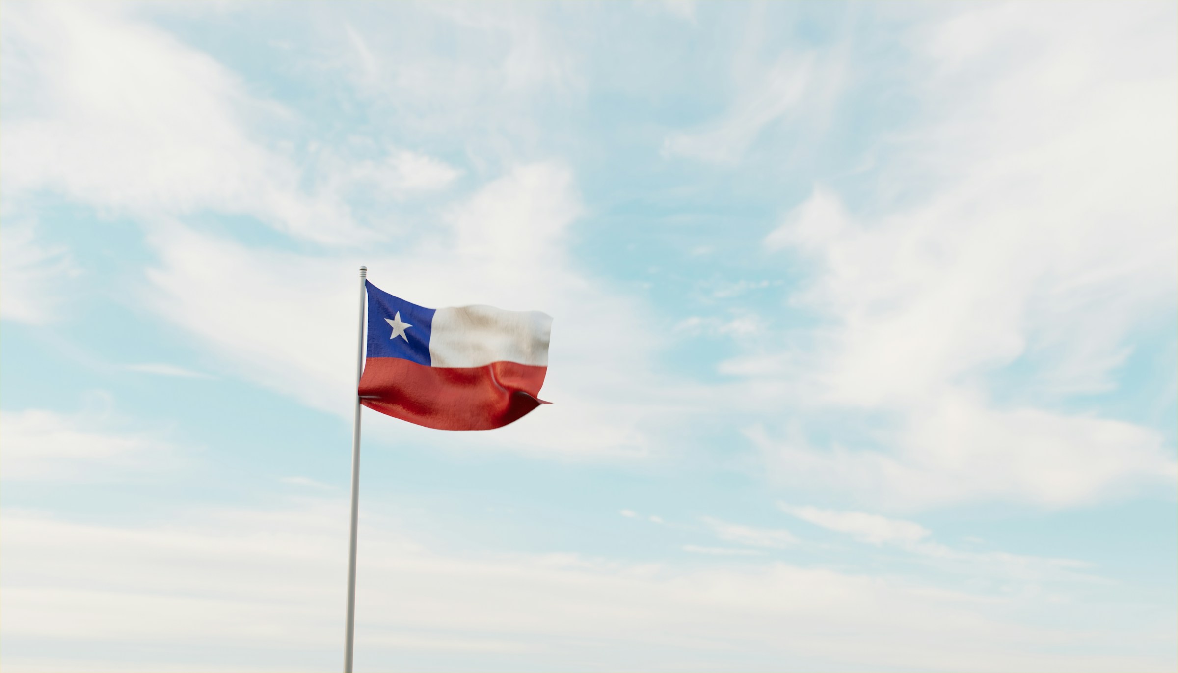 Chilean flag waving against a clear blue sky with scattered clouds.