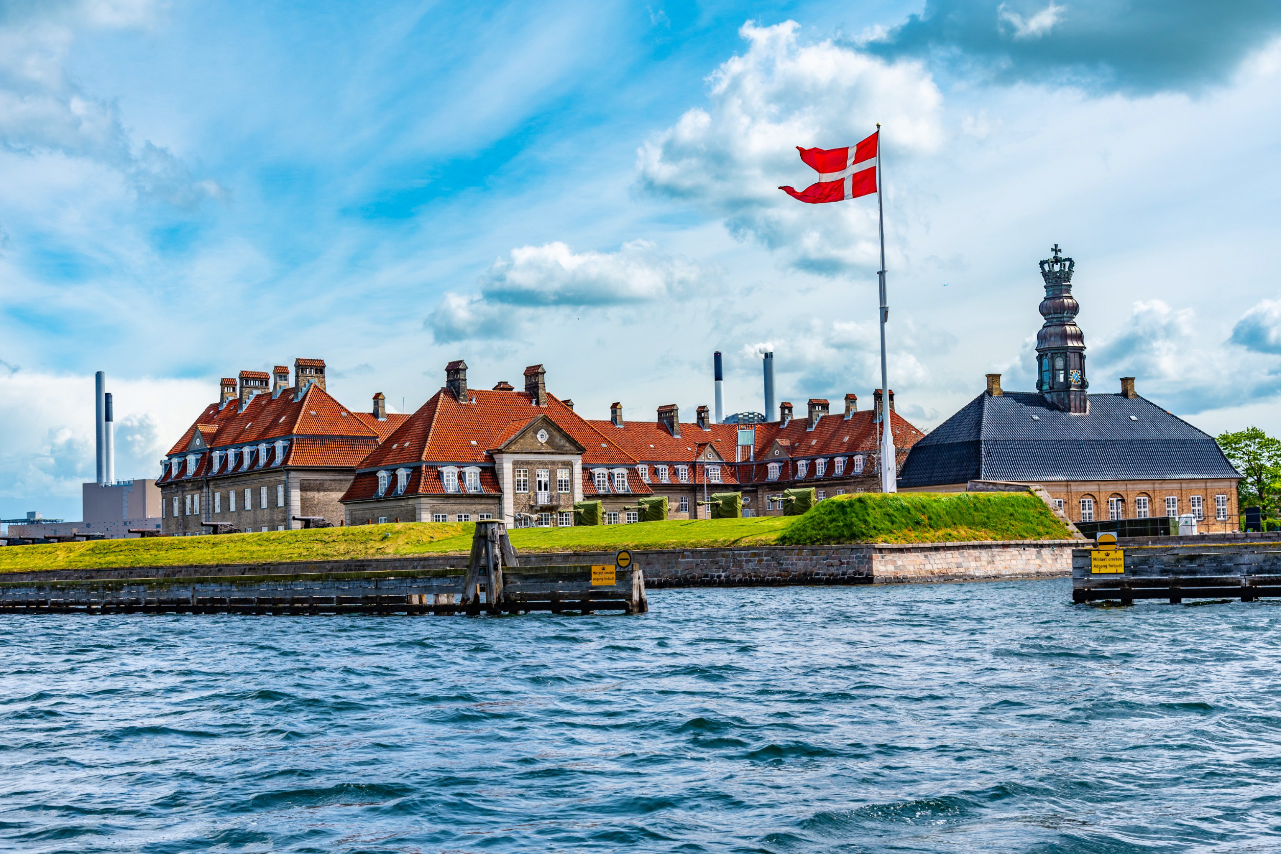 Historisk bygning ved sjøen med dansk flagg i København, Danmark, under en blå himmel
