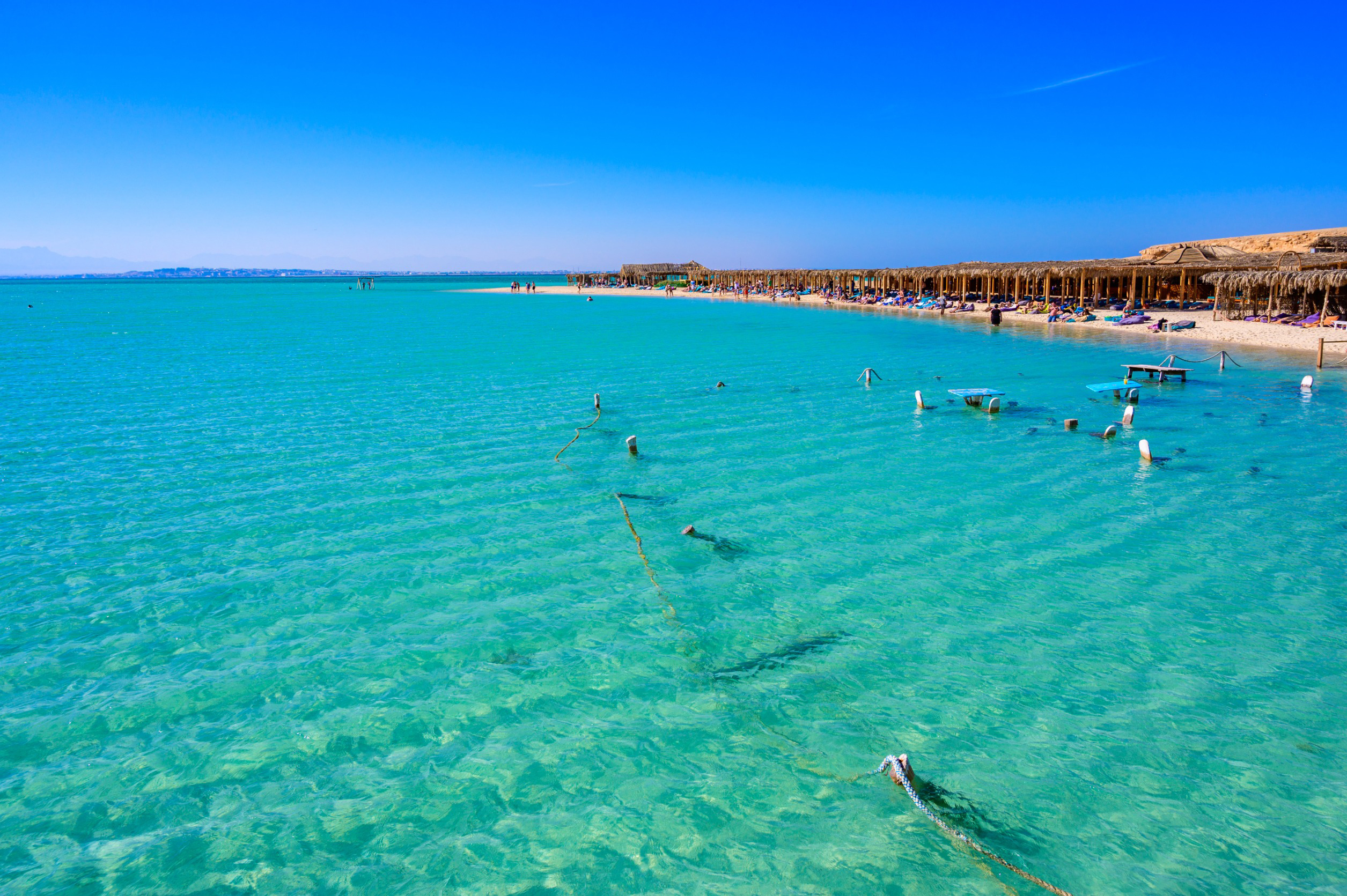 Klart turkis vann og hvit sandstrand med parasoller på Elafonissi-stranden, Kreta. Perfekt feriedestinasjon under blå himmel