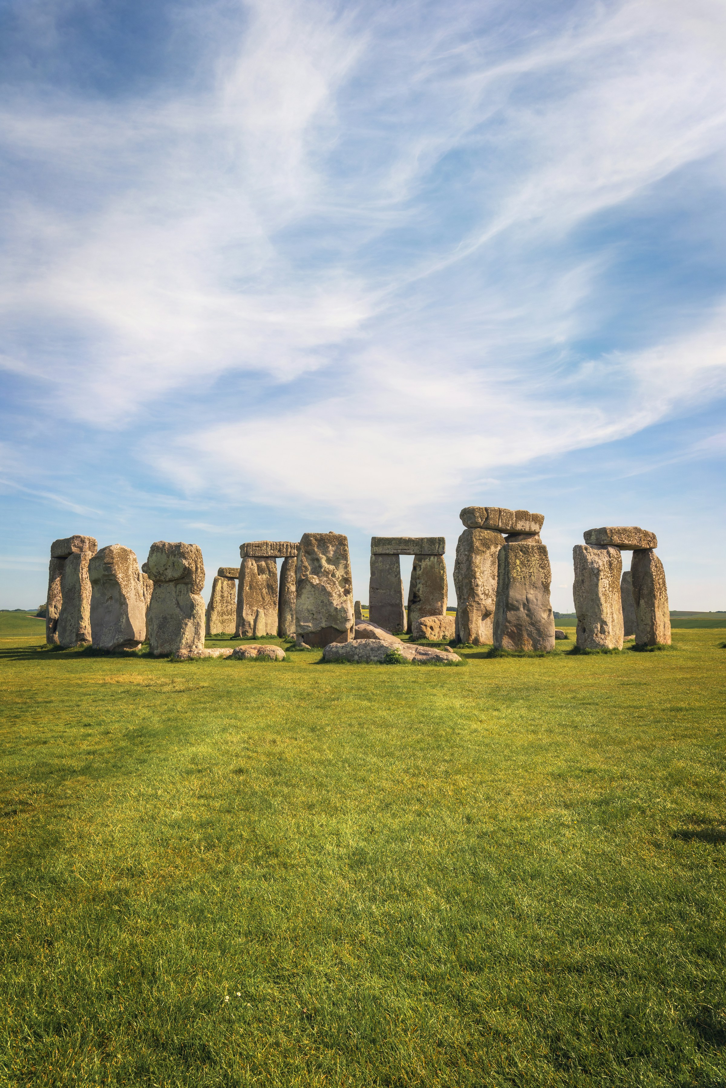 Stonehenge on a grassy field under a blue sky with clouds in England.