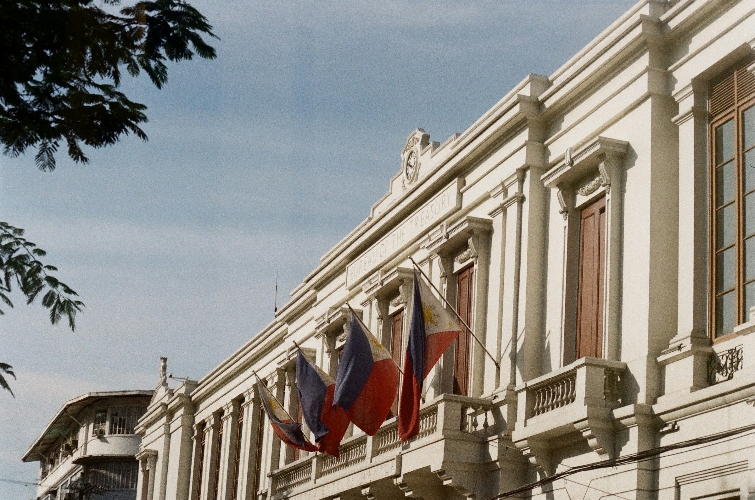 Historic building with flags outside, featuring classic architecture and a clear sky backdrop.