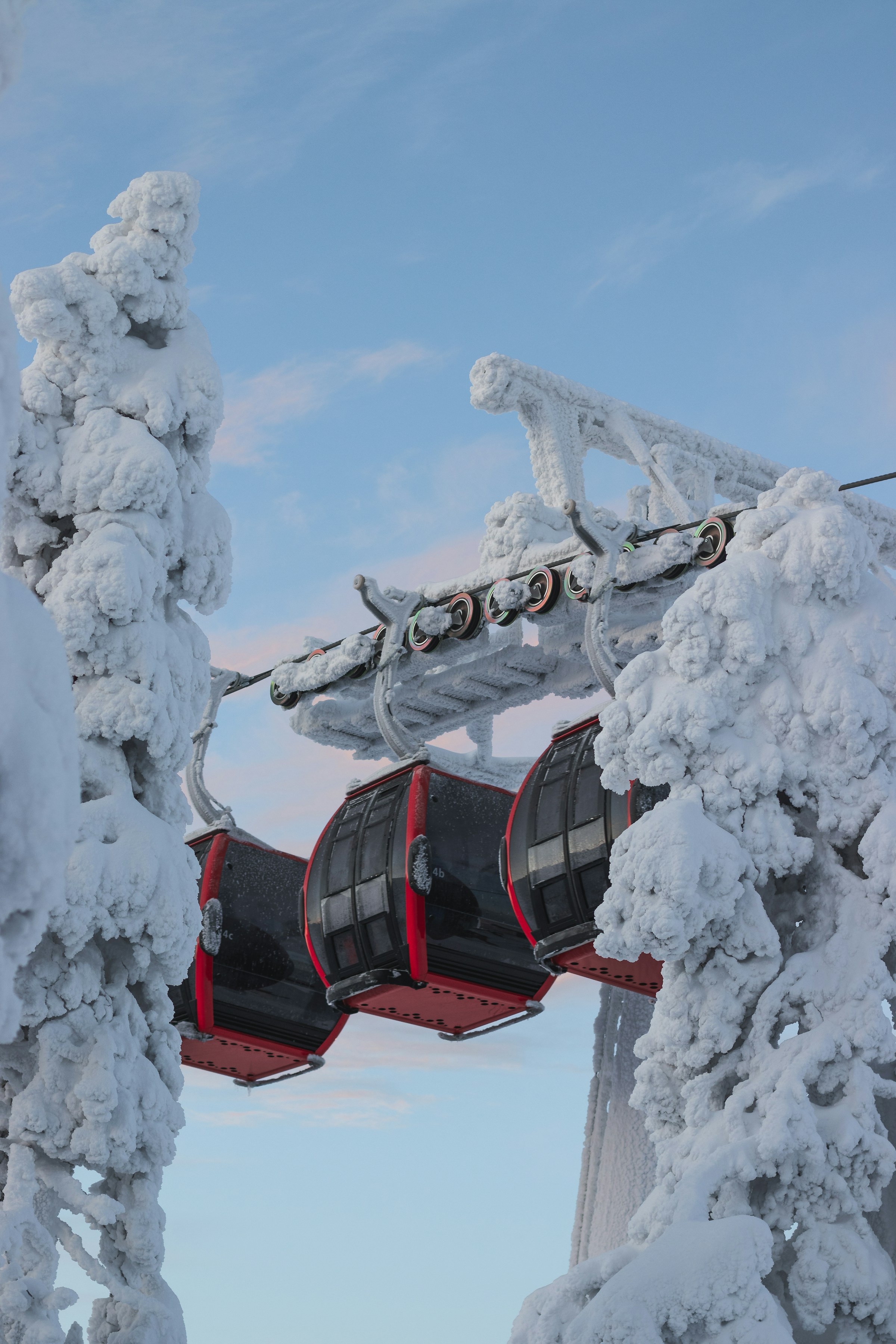 Rød skiheis og heis mellom snødekte tretopper i Ruka, Finland