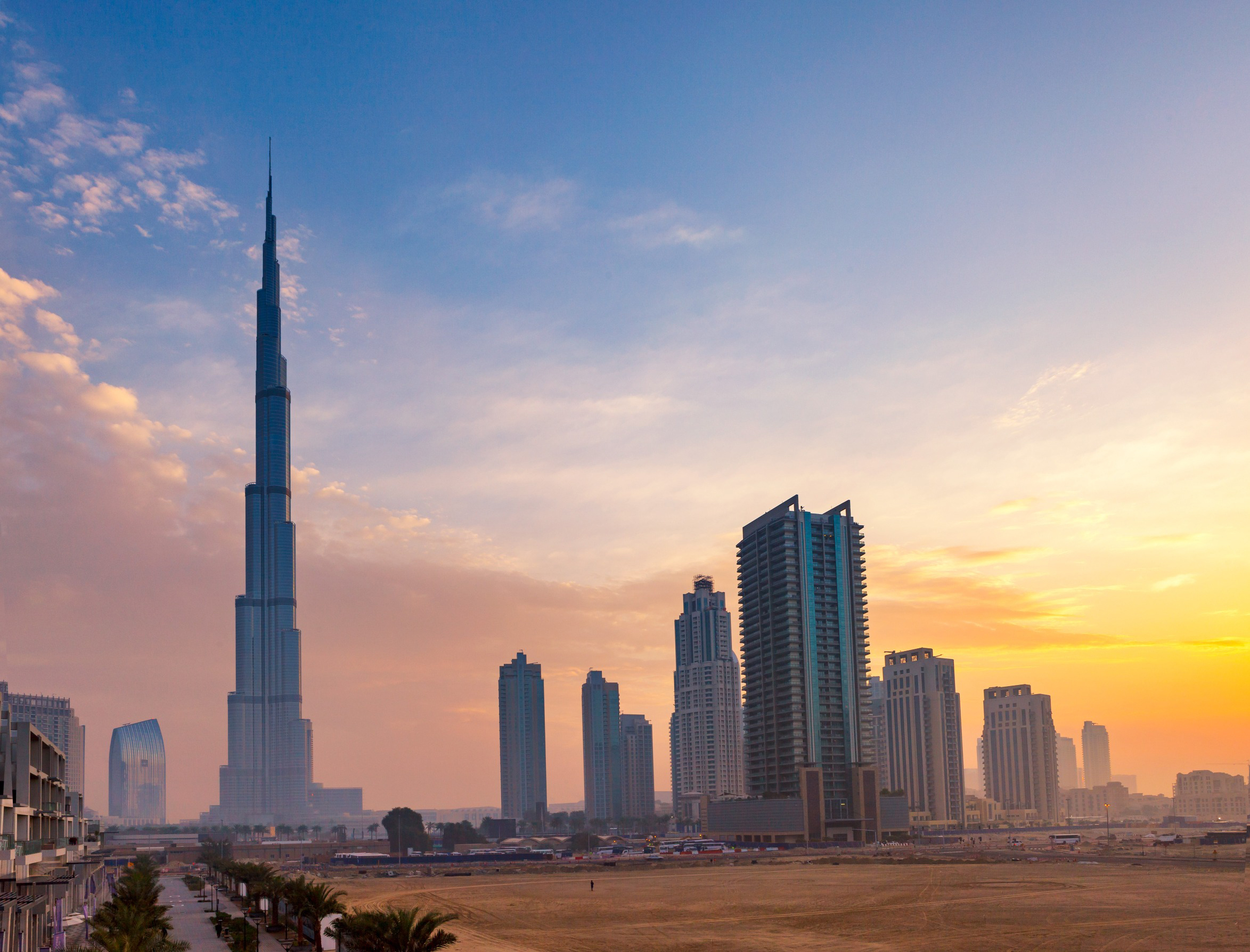 Dubai skyline med Burj Khalifa ved solnedgang. Moderne skyskrapere og klar himmel danner en imponerende bysilhuett