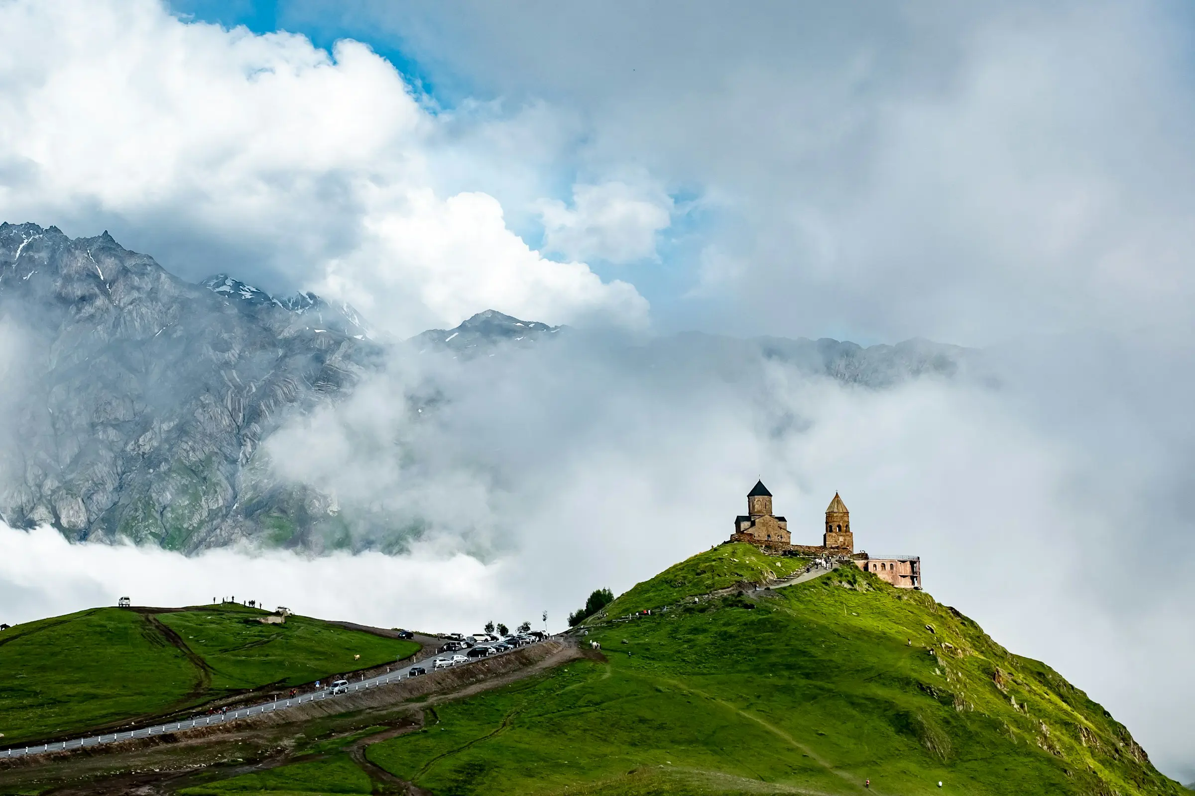 Mountaintop church surrounded by lush green landscape and mist-shrouded mountains in the background of Georgia.