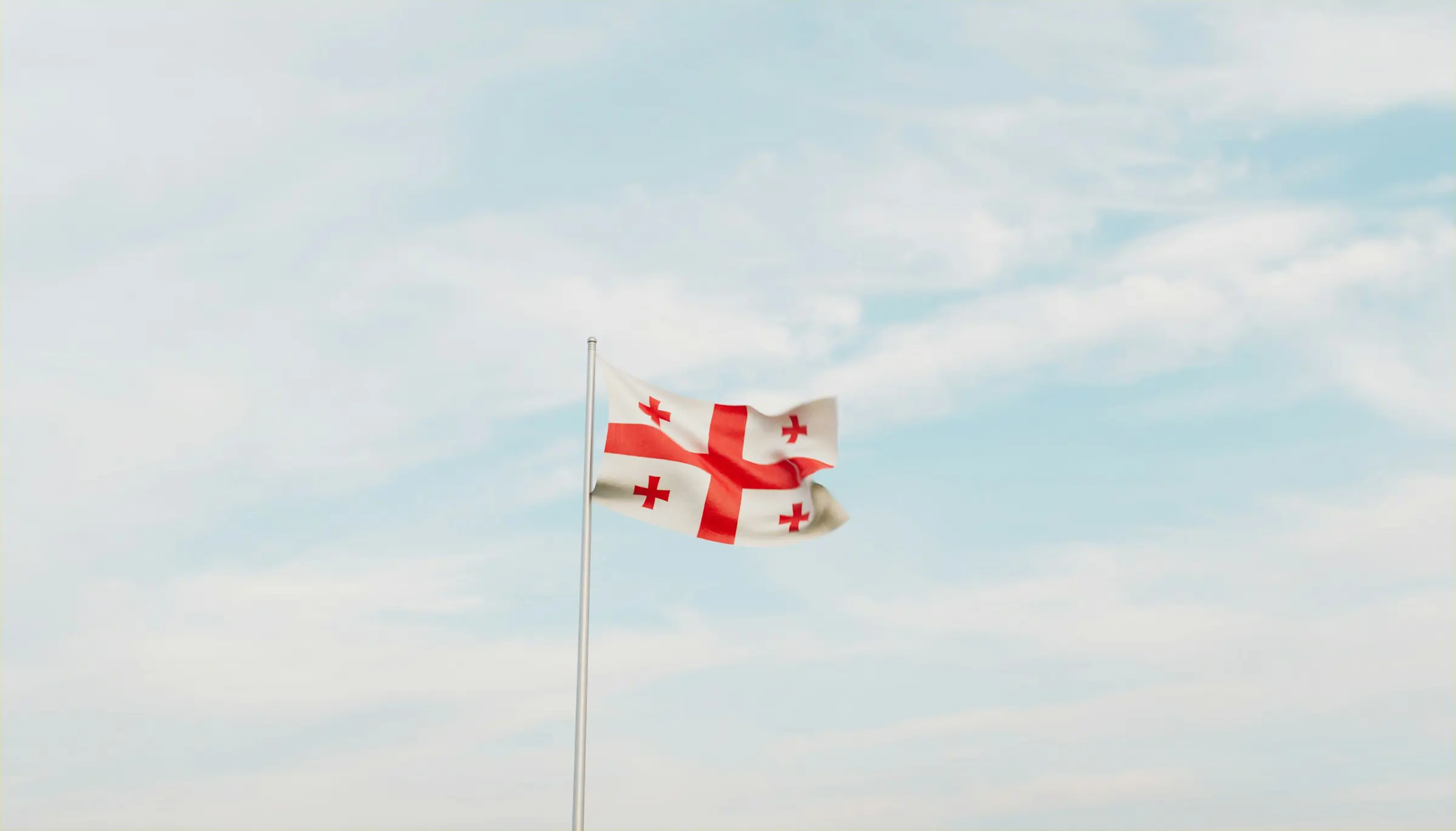 Georgia's flag flies against a clear blue sky.