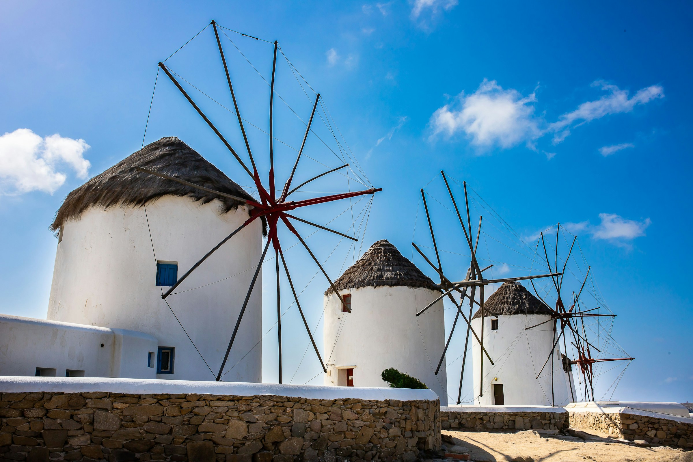 Traditional white windmills under blue sky in Mykonos, Greece.