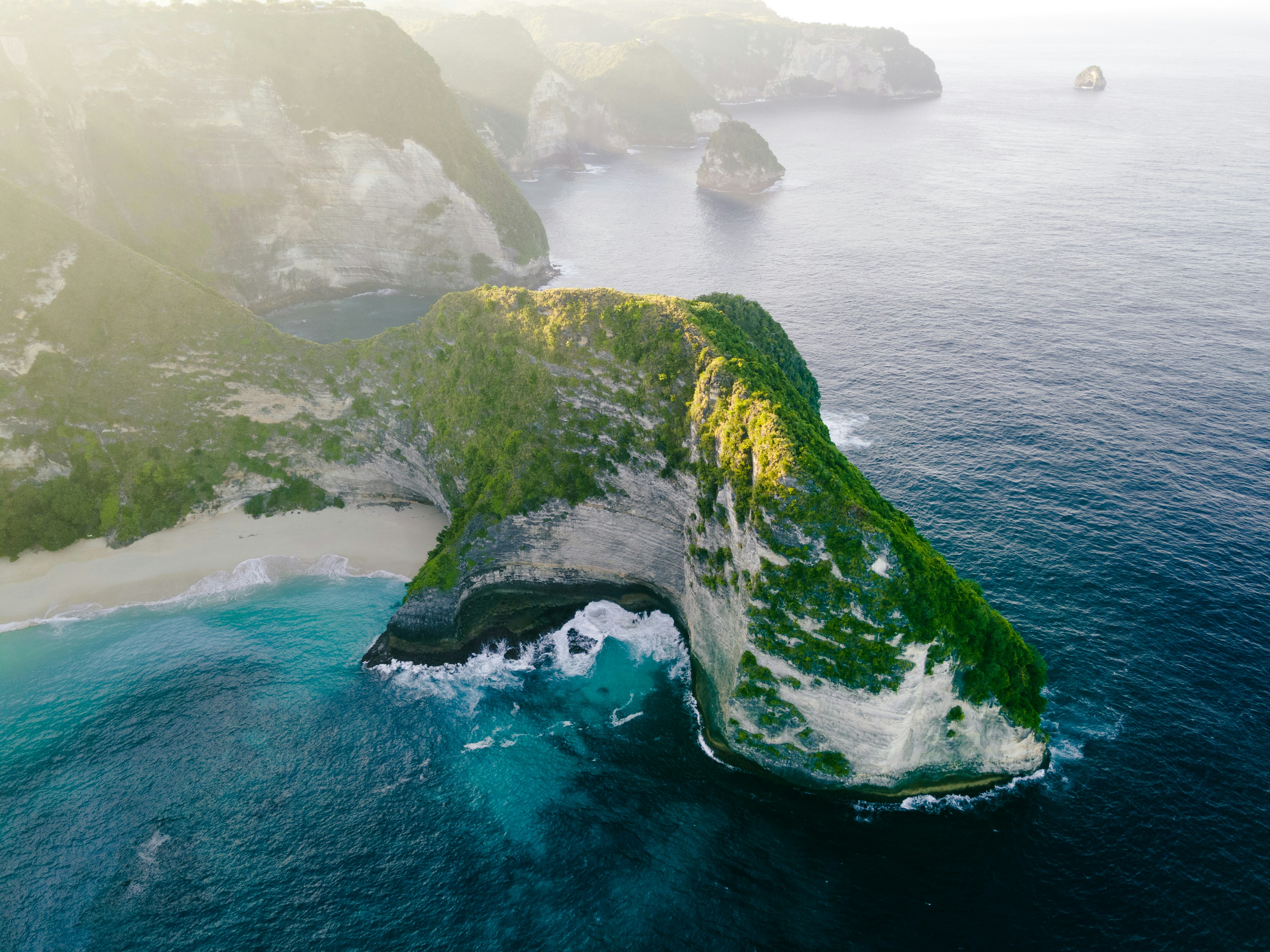 Aerial view of Kelingking Beach on Nusa Penida Island, Indonesia, featuring a T-rex-shaped cliff and turquoise waters.