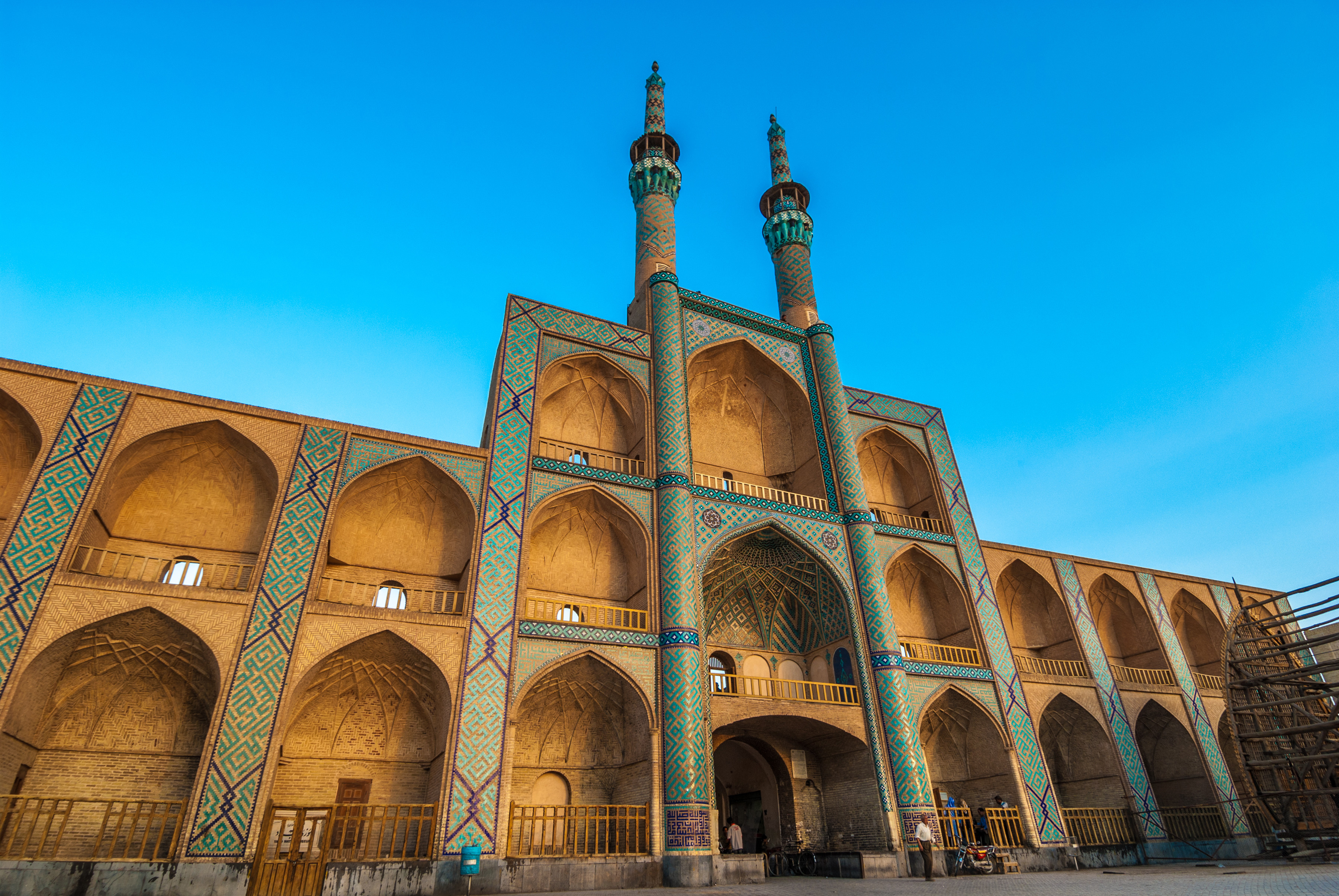 Fasaden av Amir Chakhmaq-komplekset i Yazd, Iran, med vakker persisk arkitektur og to minareter, mot en klar blå himmel