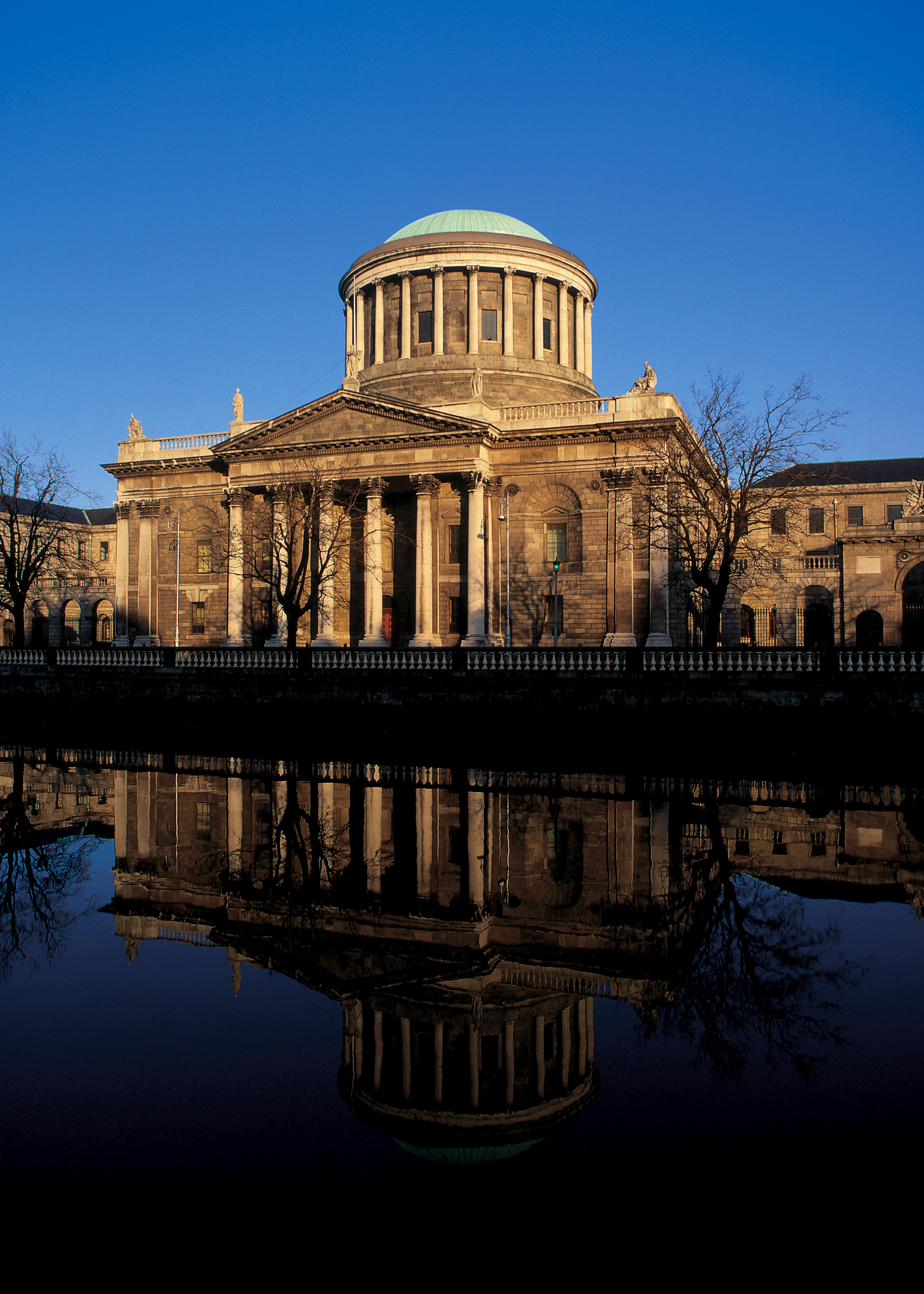 Historisk bygning med kuppel, med refleksjon i vann, mot en klar blå himmel