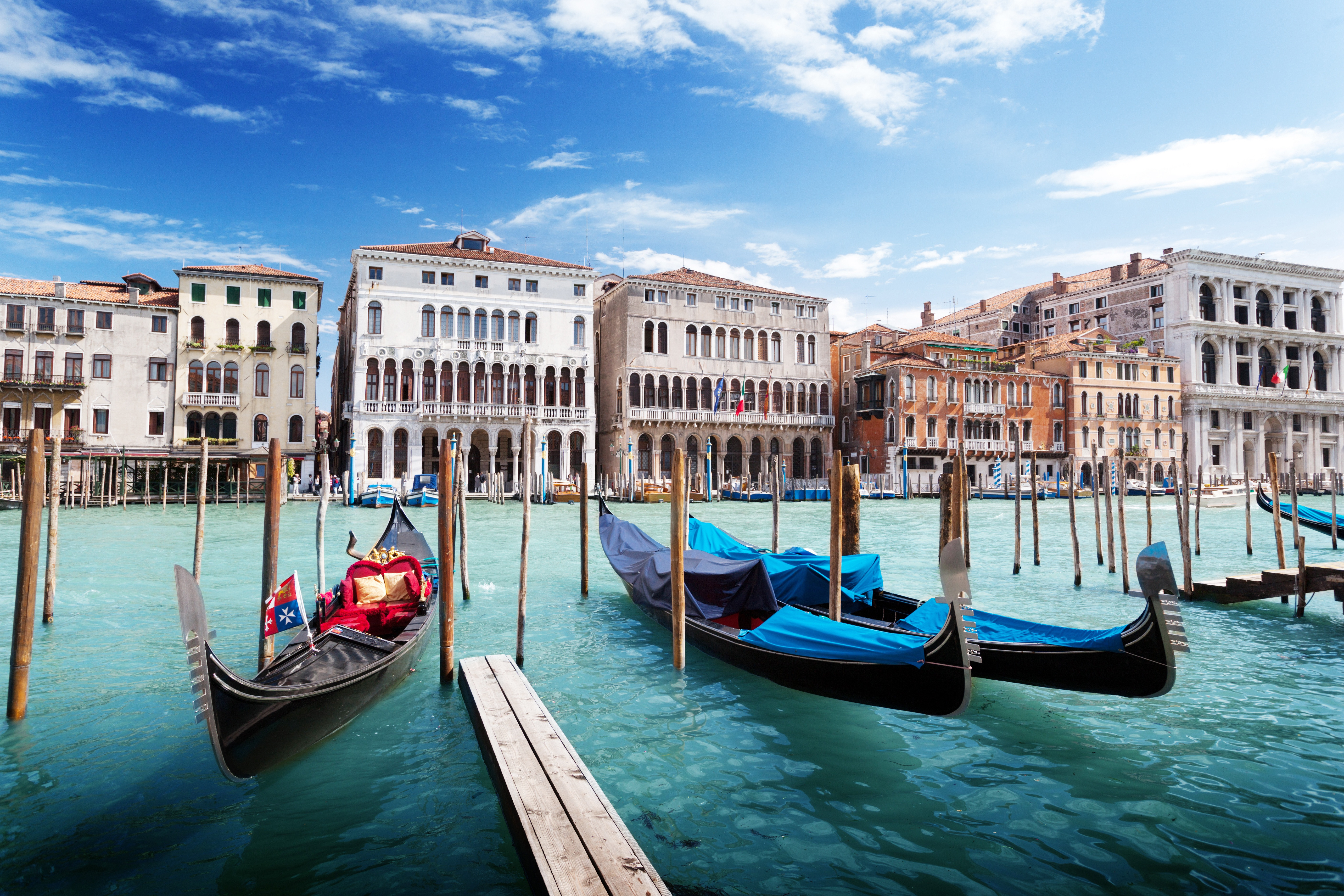 Gondoler på Canal Grande i Venezia med historiske bygninger i bakgrunnen under en klar blå himmel