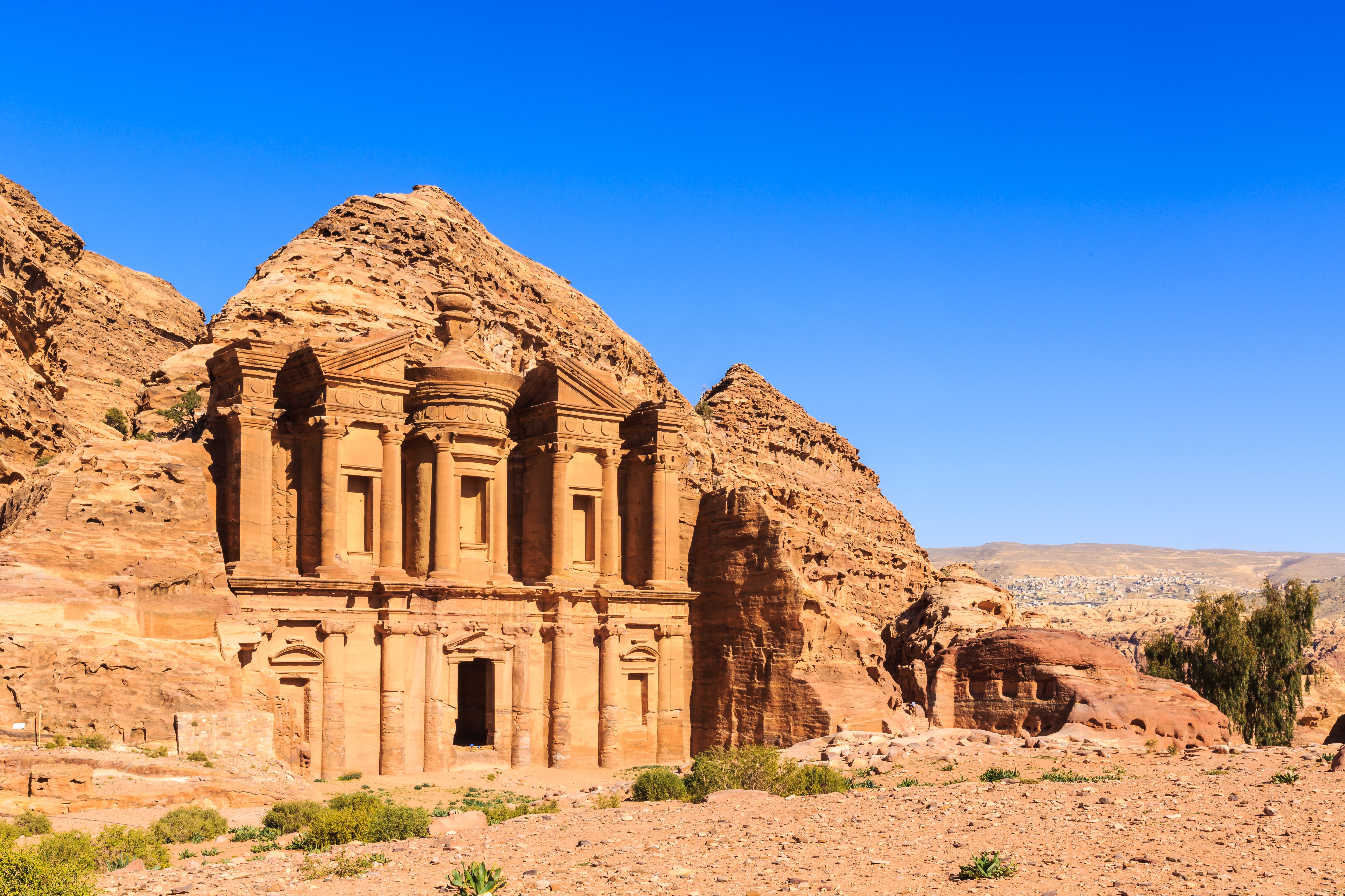 Travel to Jordan - Ancient rock-cut architecture of the Monastery in Petra, against a clear blue sky.