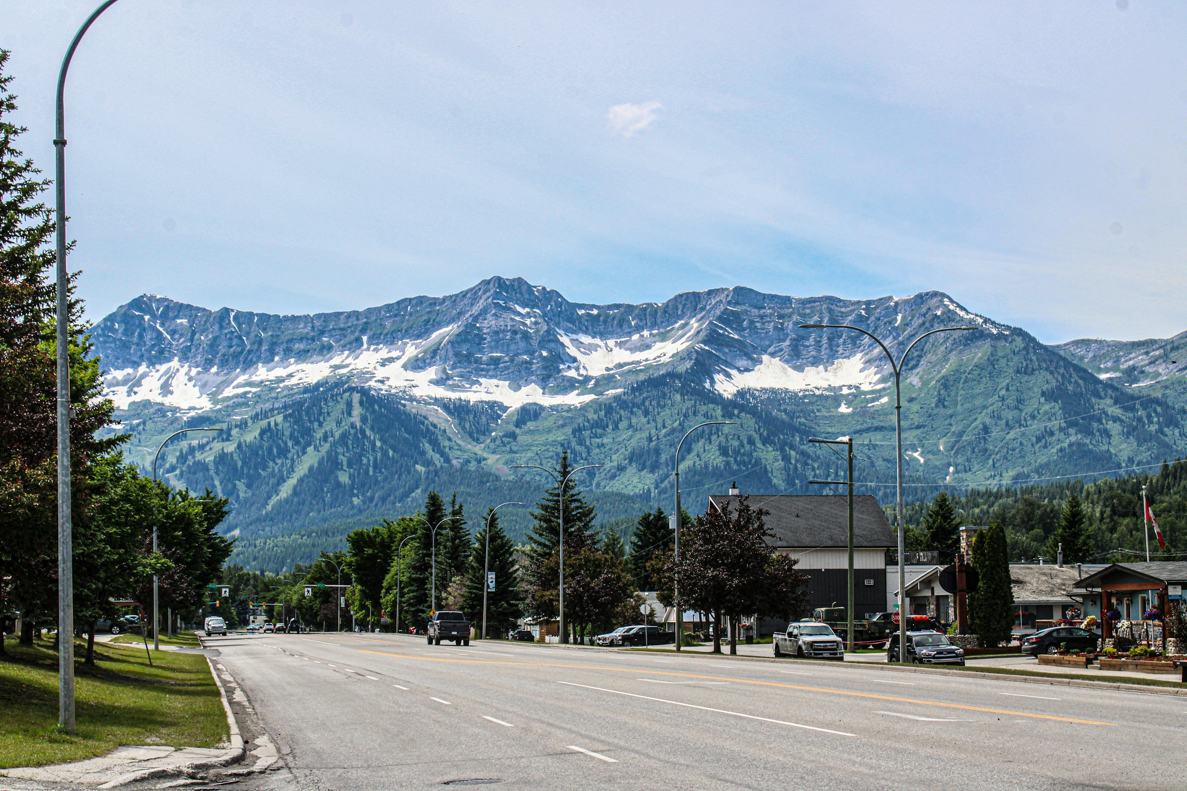 Bygate med utsikt over snødekte fjelltopper og grønne bakker under en klar blå himmel i Fernie, Canada.