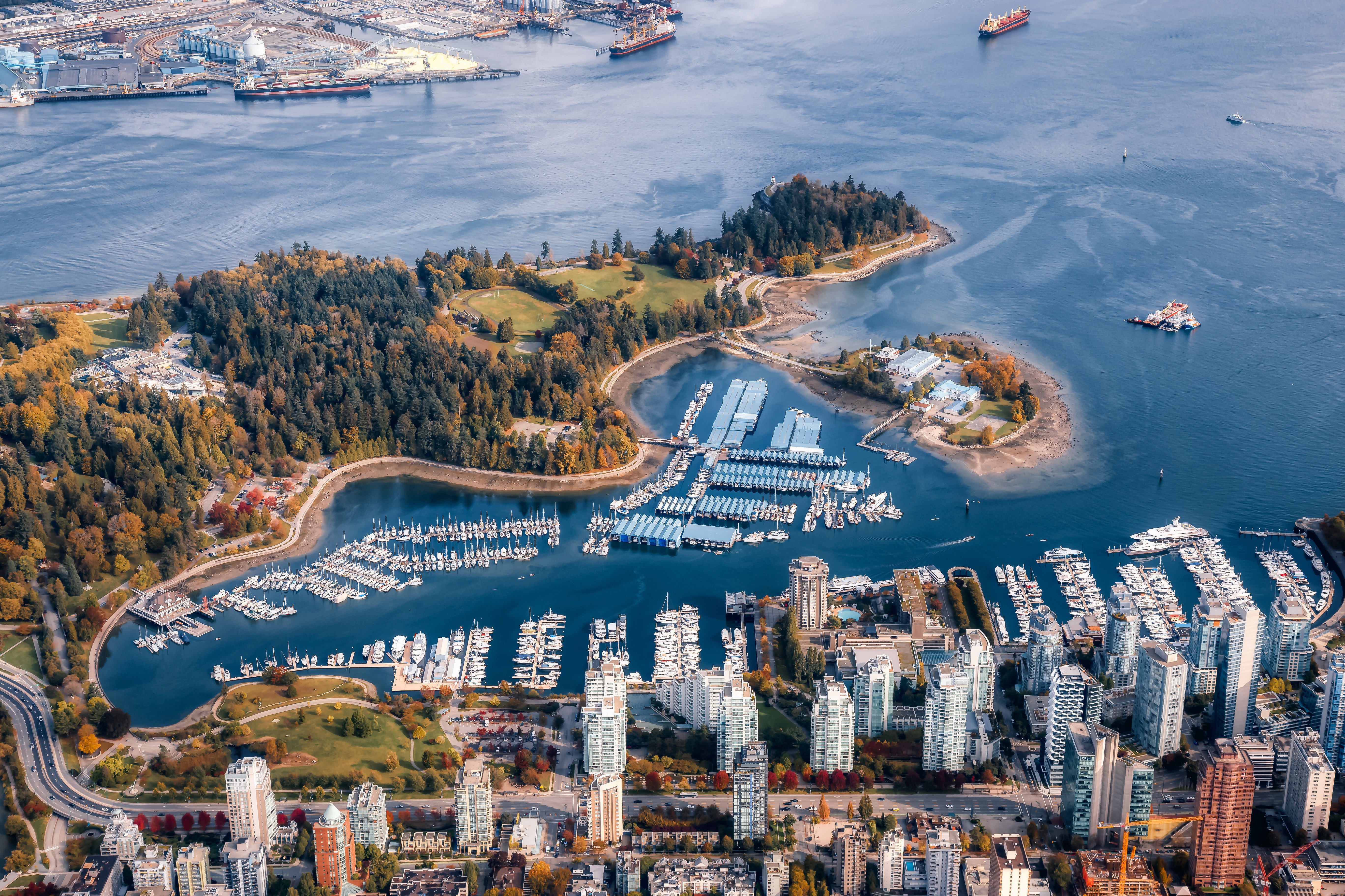 Luftfoto av Stanley Park med marinaen og Vancouver havn i forgrunnen, omgitt av høyhus og naturskjønne skoger