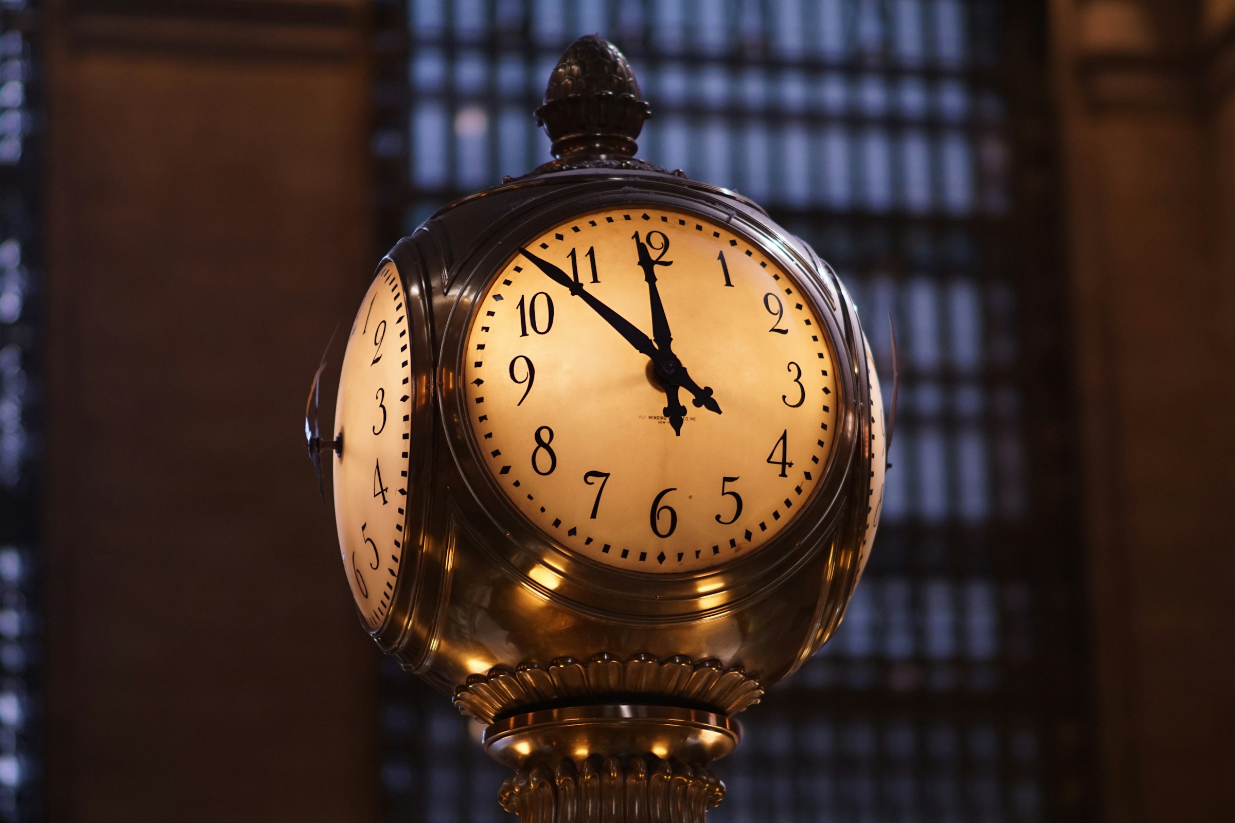An ornate clock inside Grand Central Terminal showing the time as 10:10, with a dimly lit, architectural background