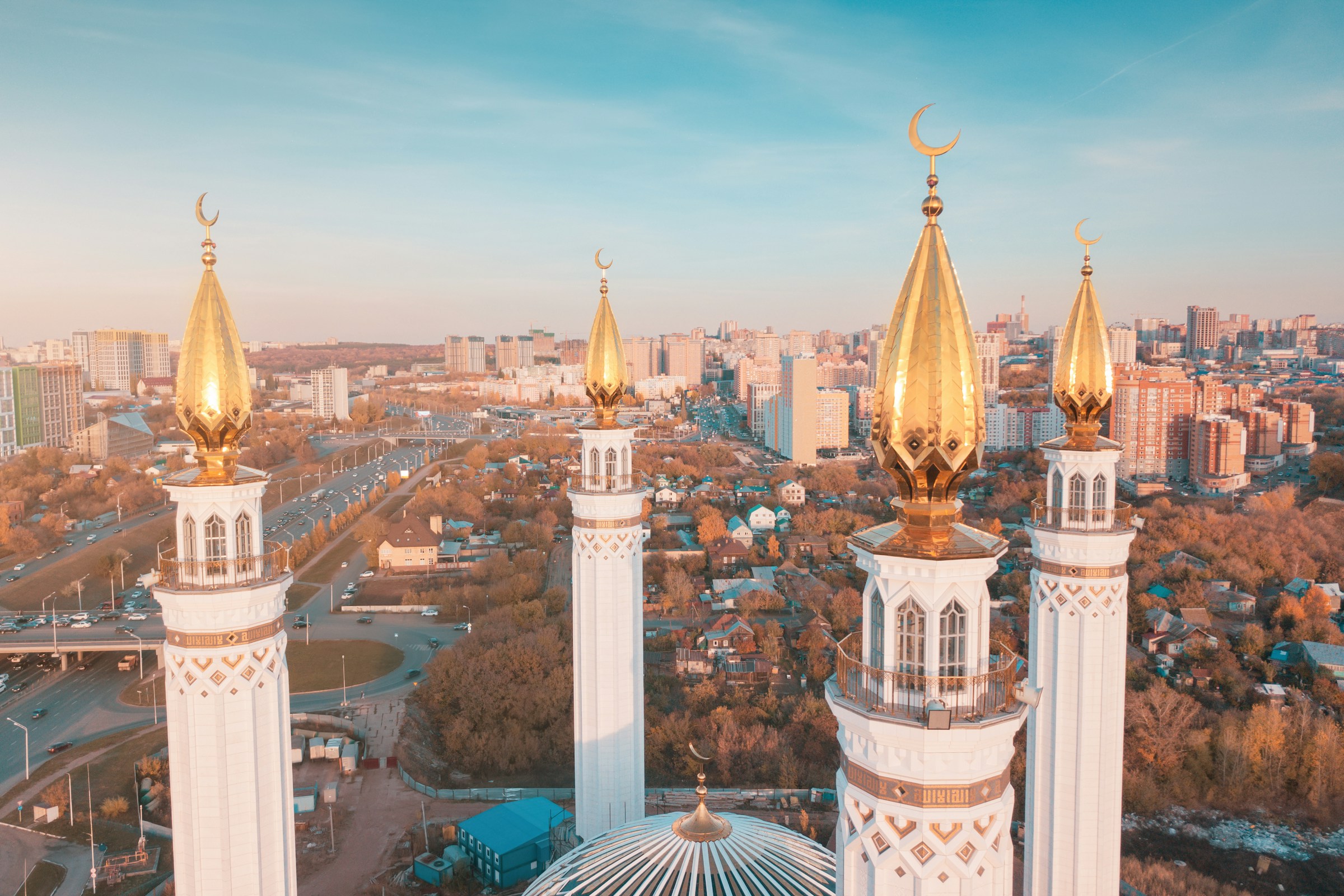 Gold-topped minarets of Safa Mosque with a city skyline in the background under a blue sky