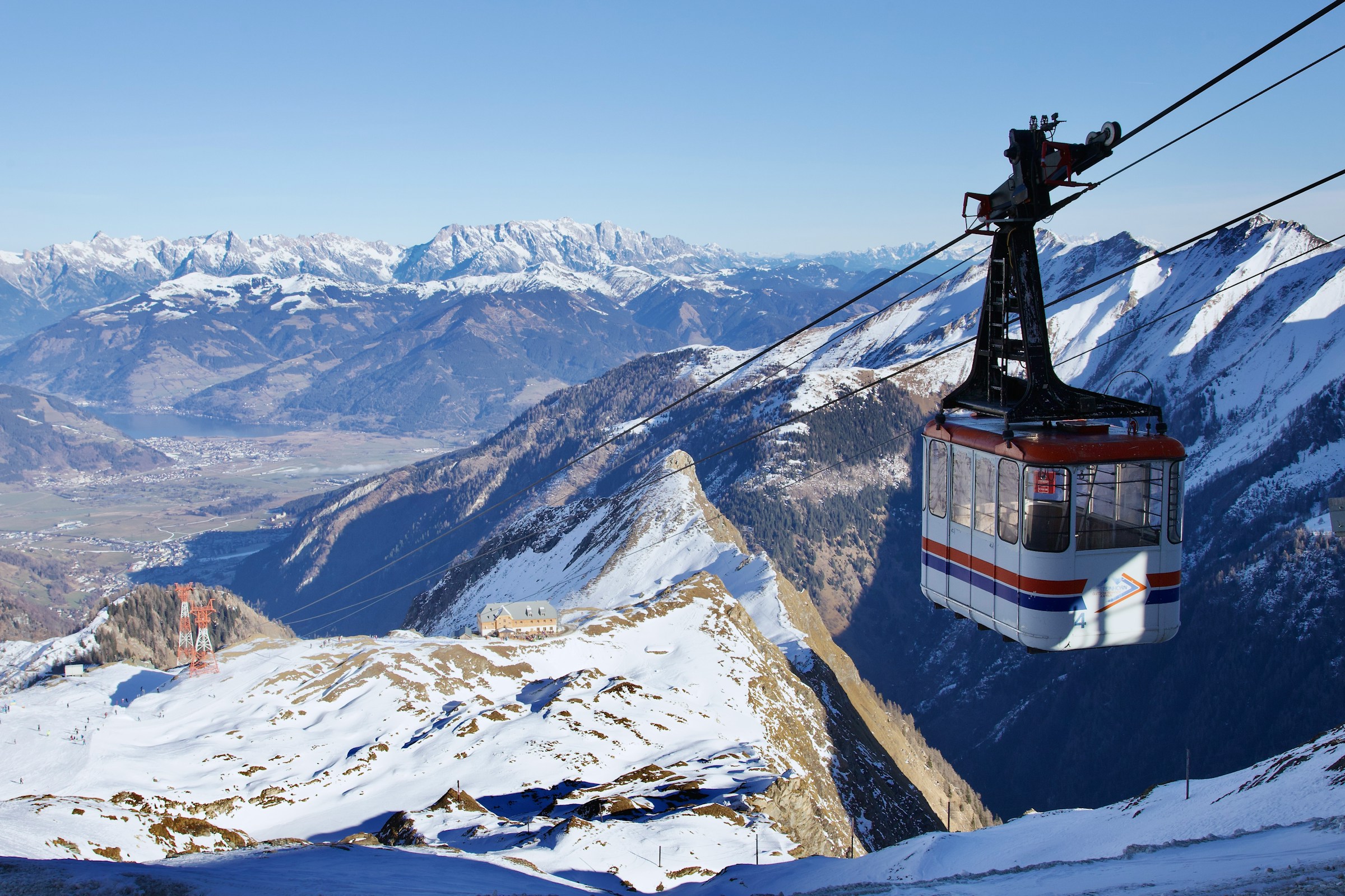 Skiheisen går ned en skibakke med mektige snødekte fjell i bakgrunnen i Zell am See