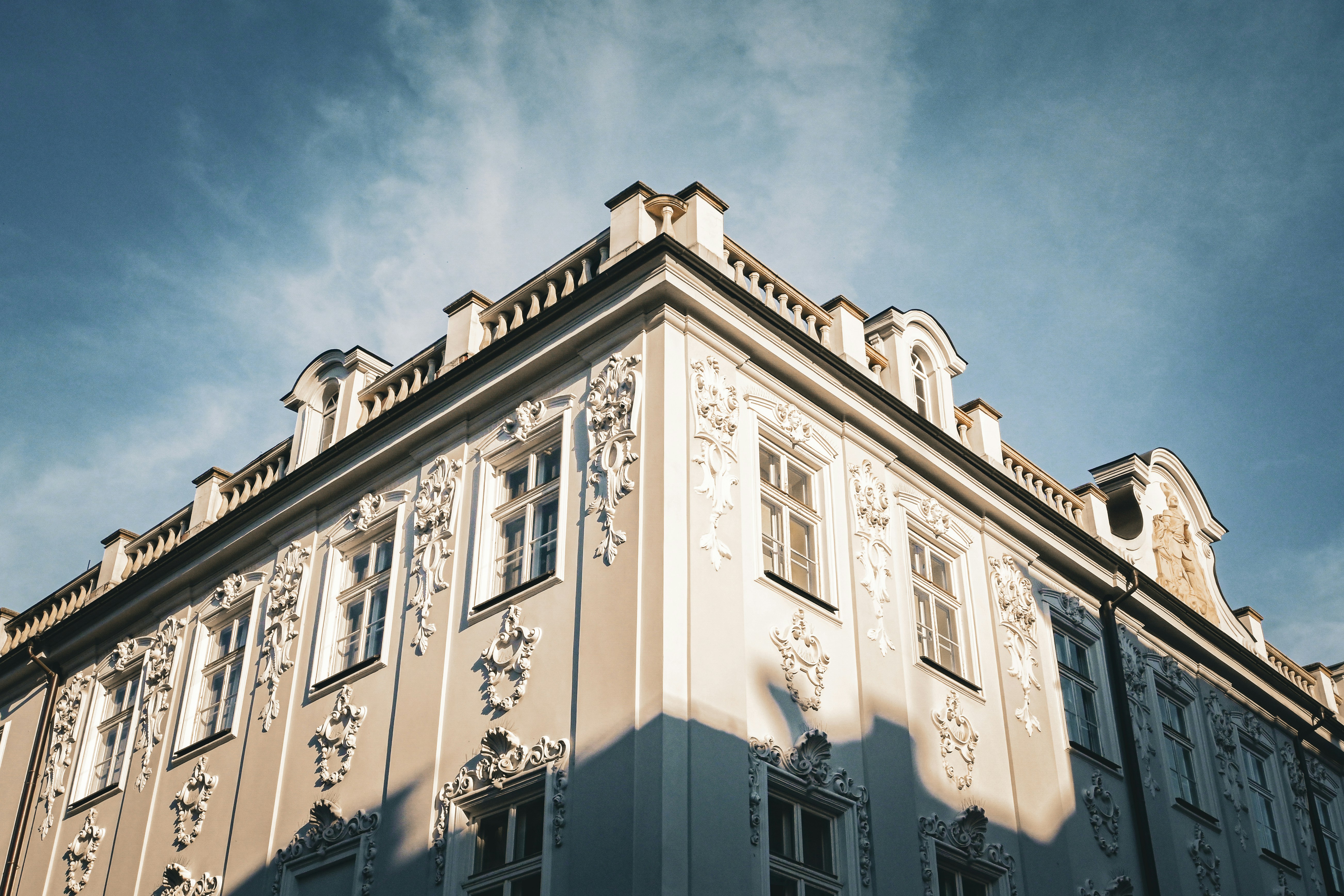 Ornate European-style building façade with decorative white stucco designs and multiple windows against a clear blue sky