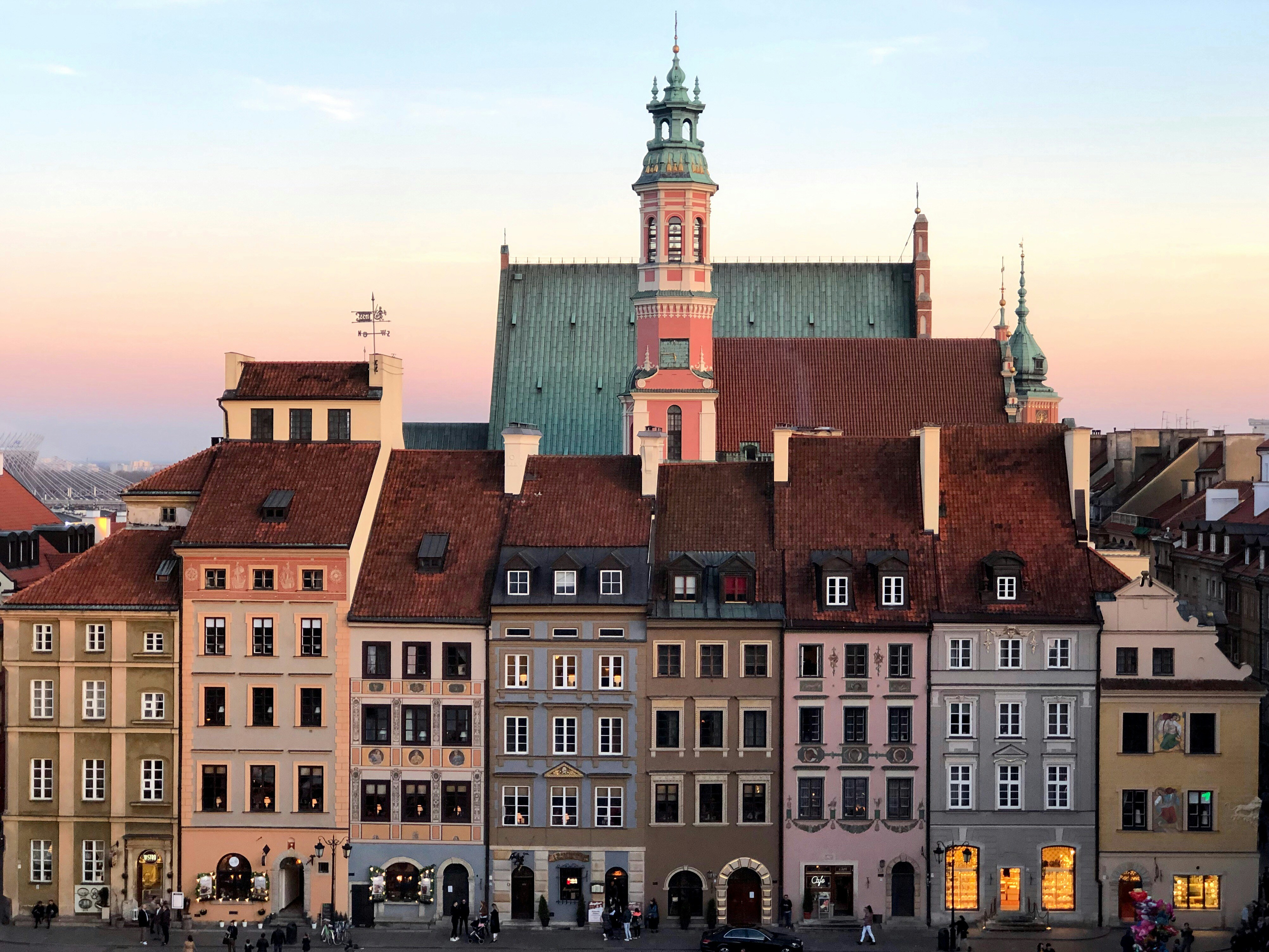 Older traditional buildings in Poland rise against the sky during a sunset