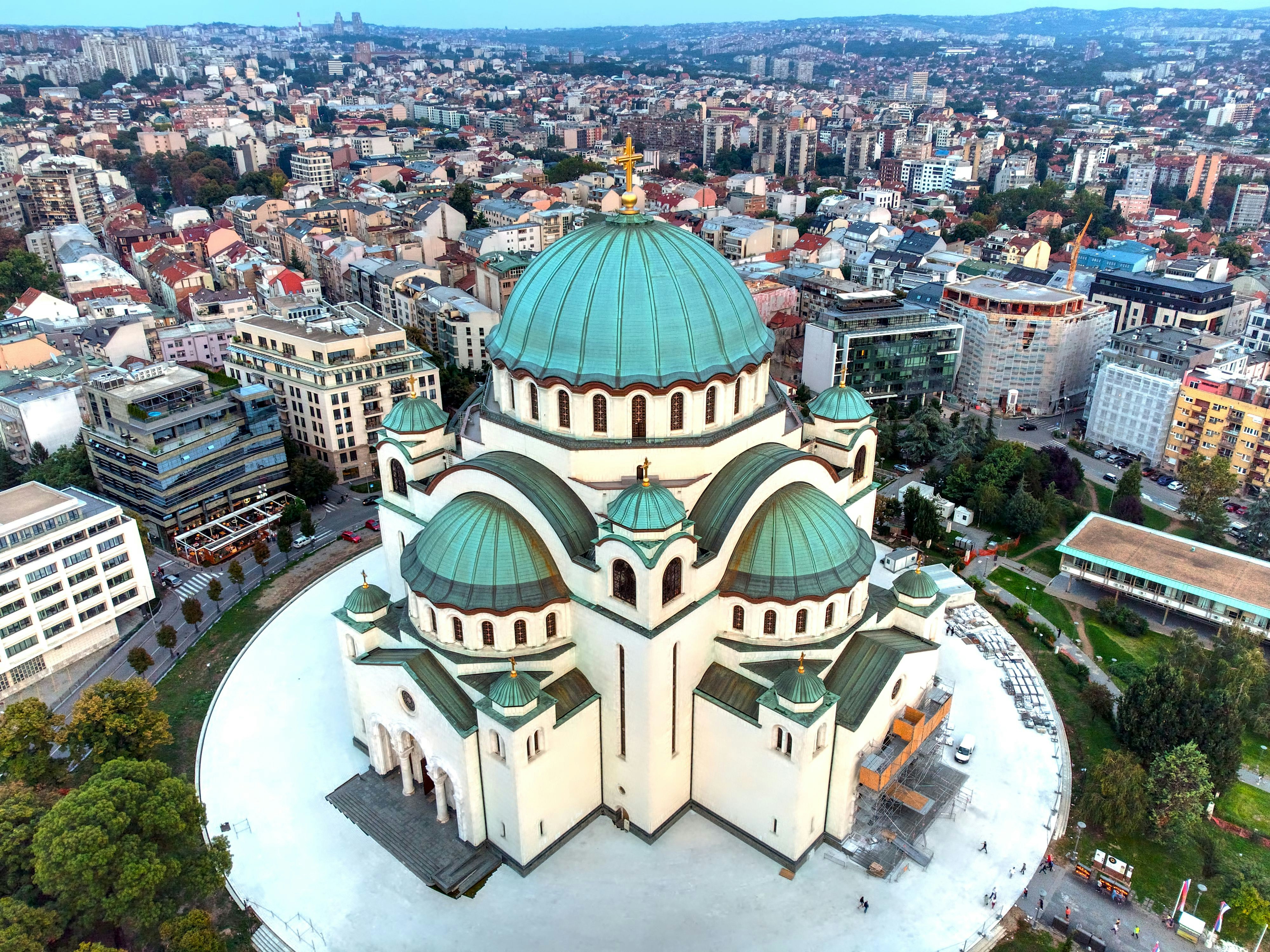 Luftfoto av St. Sava-katedralen i Beograd, med grønn kuppel og byens arkitektur i bakgrunnen
