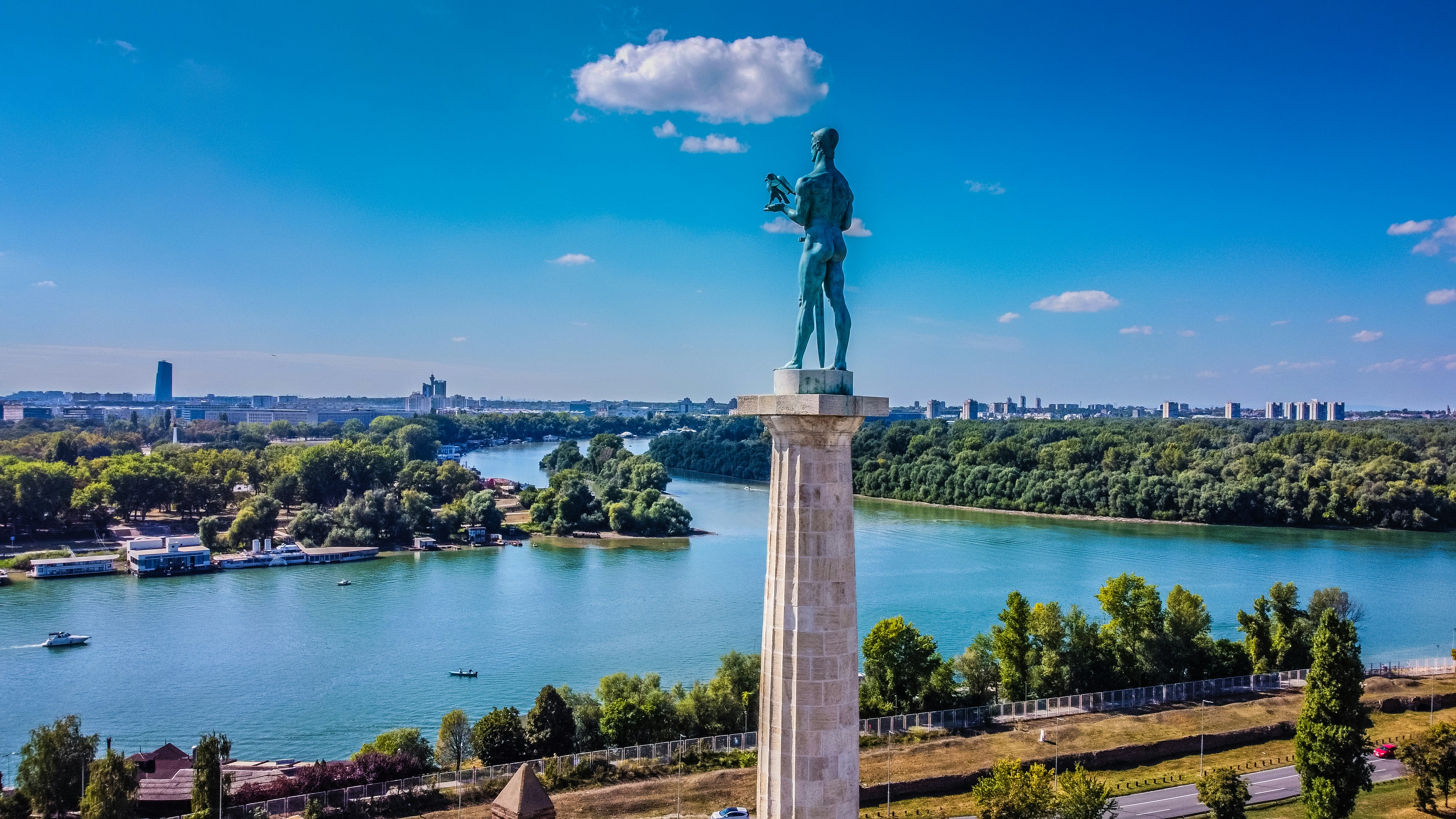Statue av Pobednik med utsikt over elvene og byens silhuett i Beograd, Serbia, under blå himmel