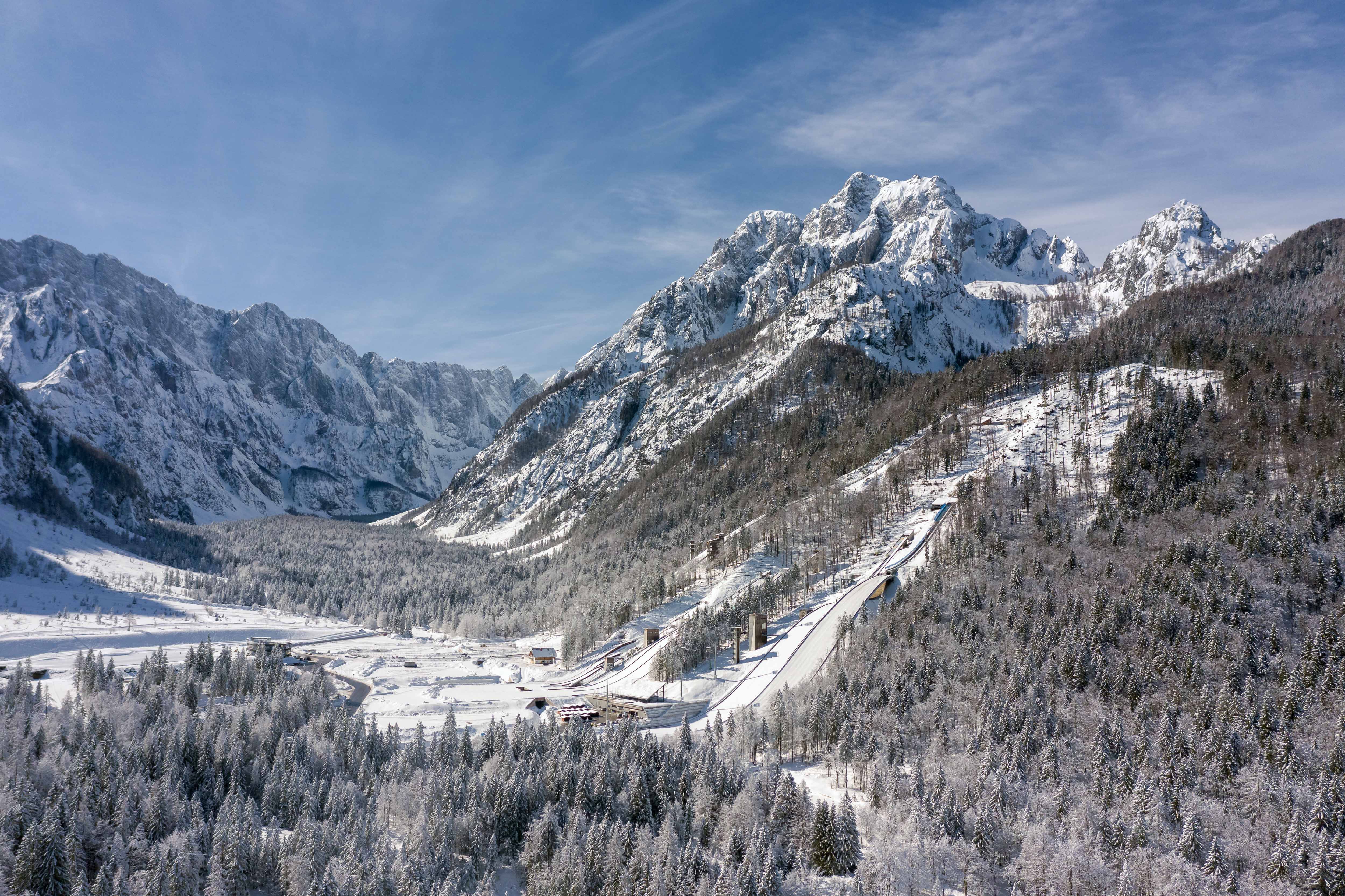 Vakkert naturlandskap i Kranjska Gora, Slovenia med snødekte fjell og skibakke nede i et skianlegg