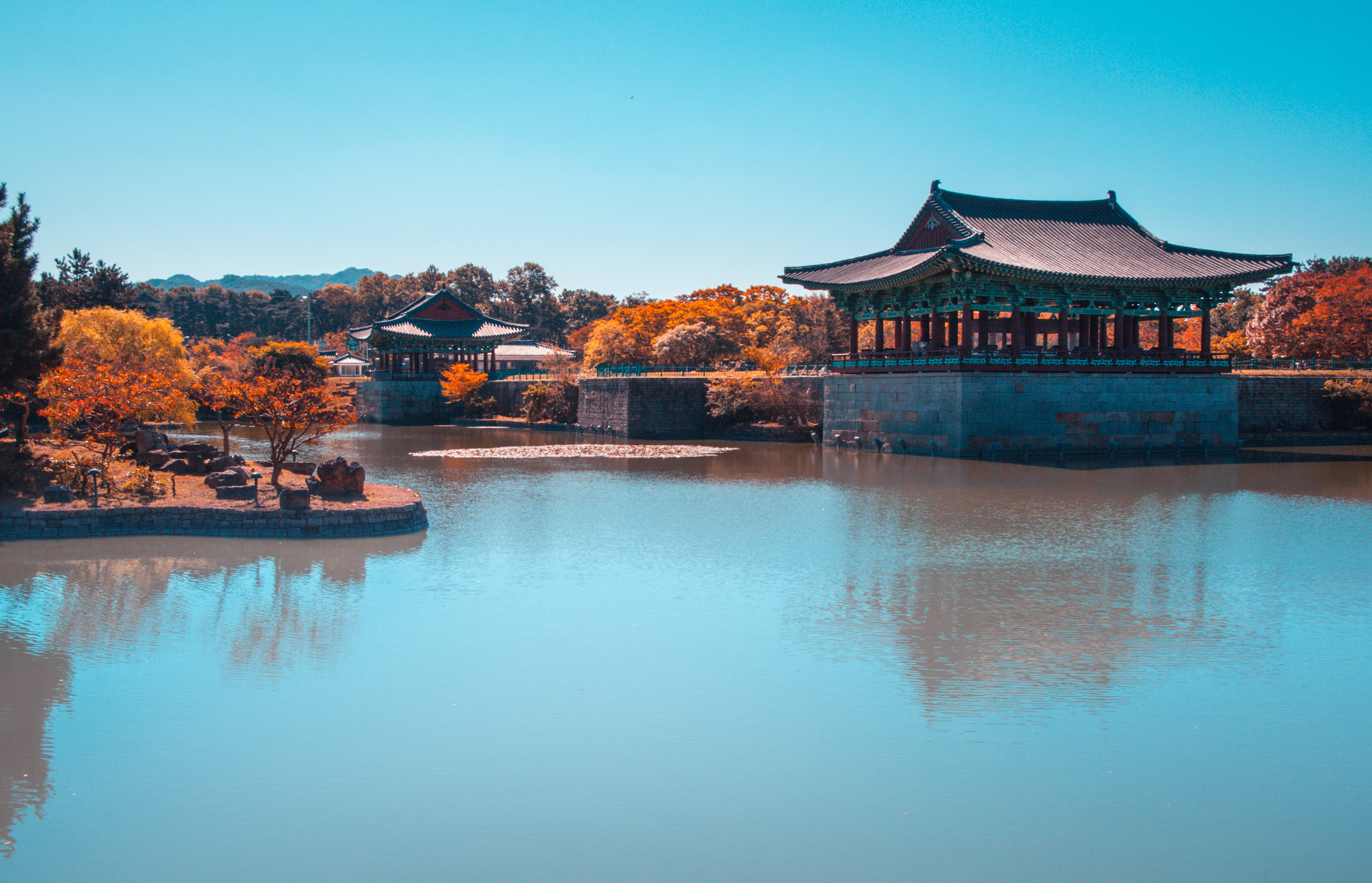 Travel to South Korea - Tranquil Korean pagoda reflected in a serene pond, surrounded by vibrant autumn foliage.