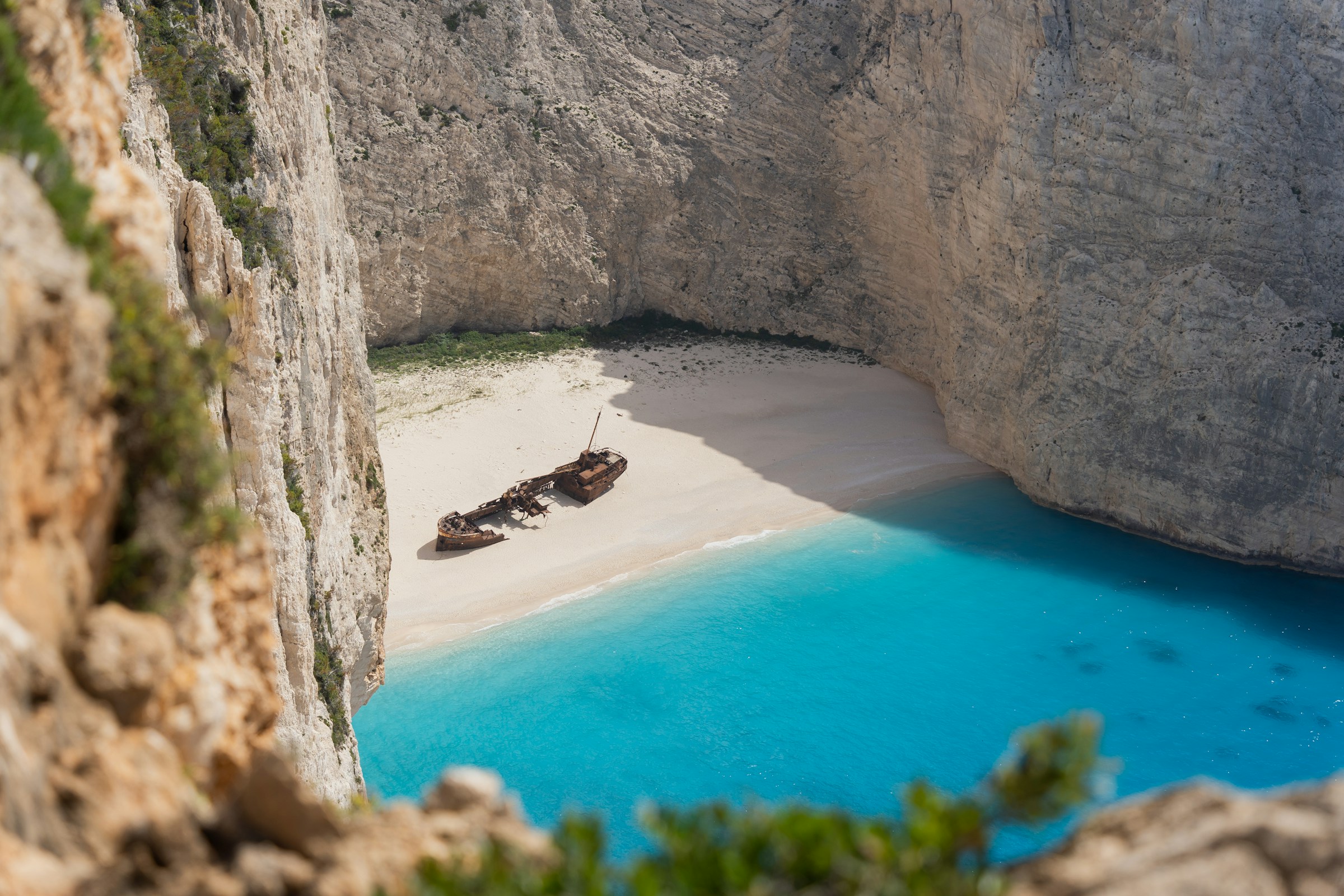 Navagio Beach in Zakynthos, Greece, featuring a famous shipwreck on white sand surrounded by turquoise waters and steep cliffs.