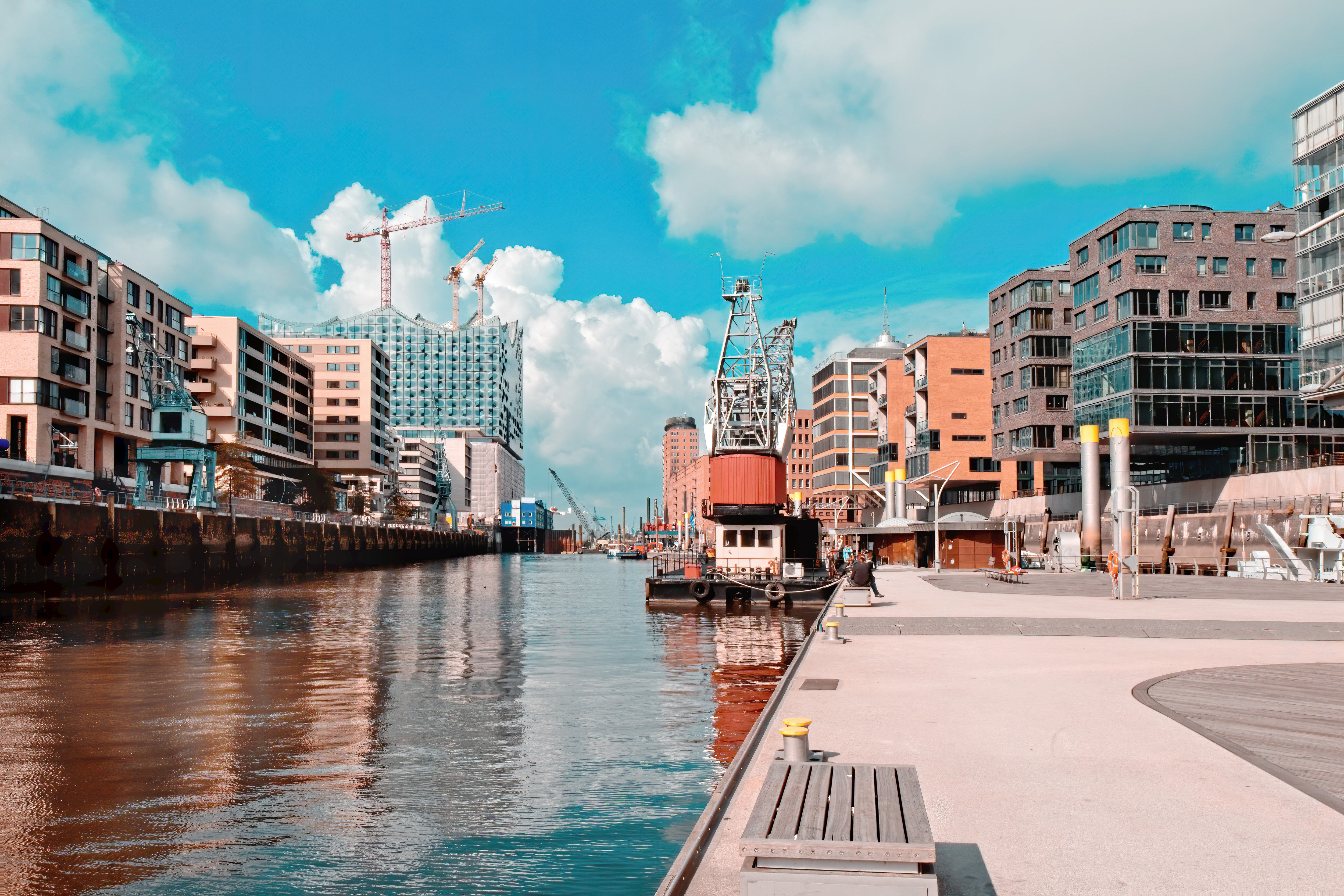 Travel to Hamburg - Hamburg's HafenCity with contemporary buildings, cranes, and moored ships on a sunny day.