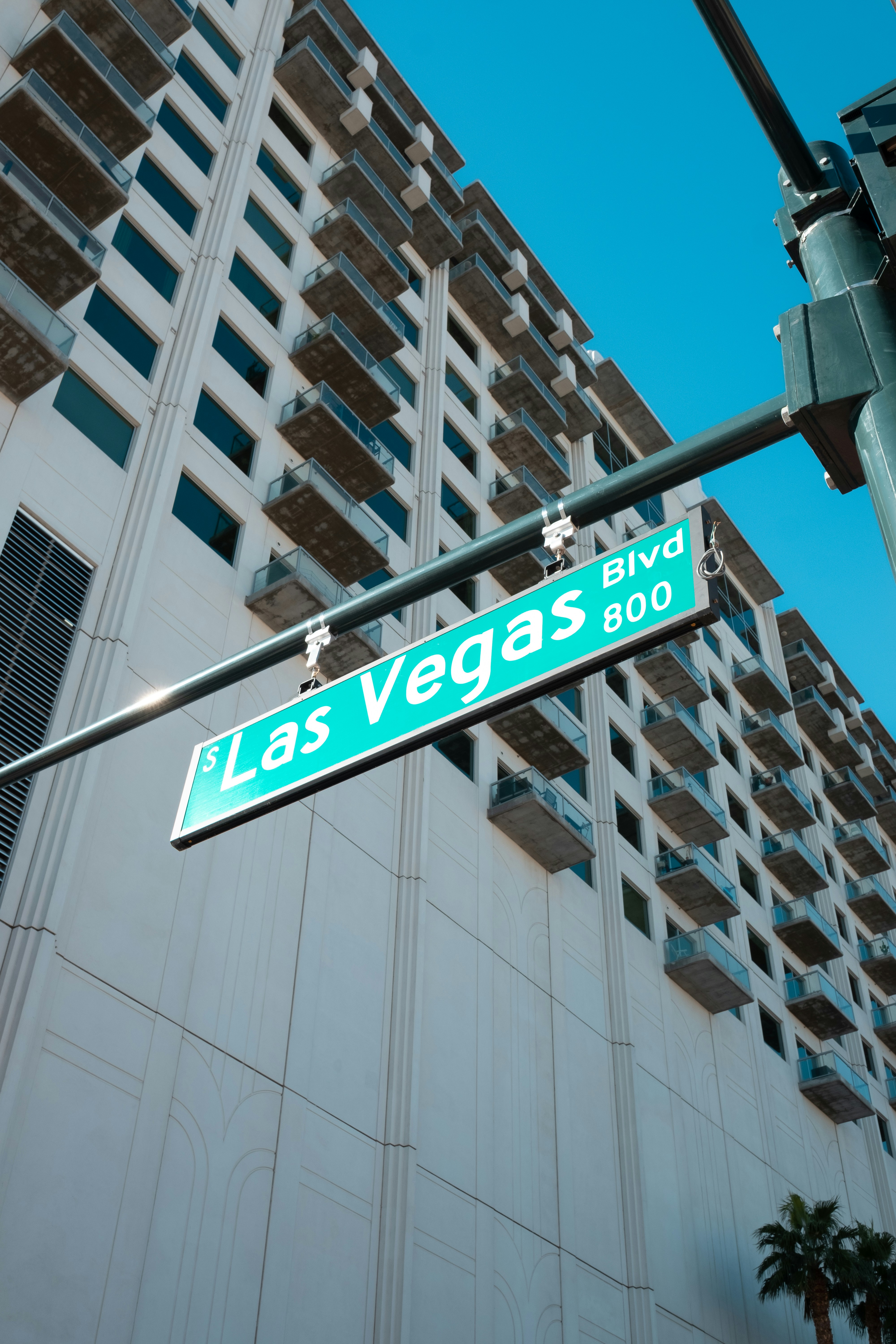 Gateskilt for Las Vegas Blvd med en høyblokk i bakgrunnen mot en klar blå himmel