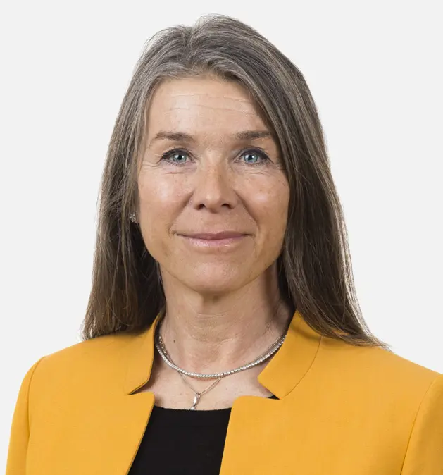 Beth Friberg - Professional woman with long hair wearing a yellow blazer and black top, facing the camera with a neutral expression.