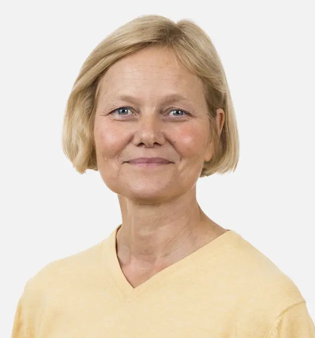 Smilende kvinne med kort blondt hår iført en gul skjorte mot en enkel hvit bakgrunn