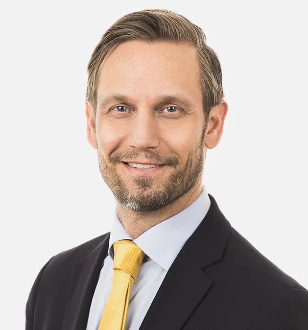 Smilende mann i dress med gul slips på en ensfarget hvit bakgrunn