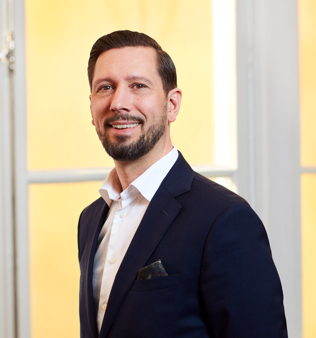 Smiling man in suit in front of a window, professional portrait.
