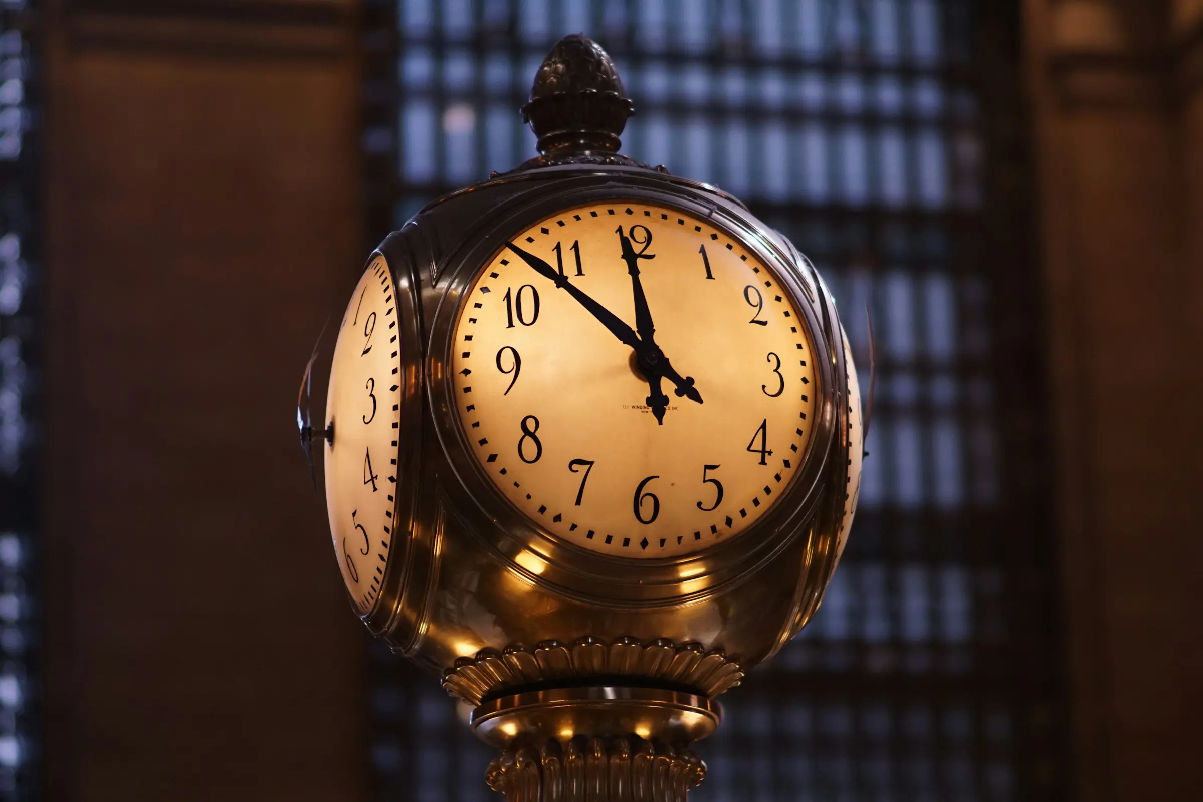 Utsmykket klokke inne i Grand Central Terminal som viser klokken 10:10, med en svakt opplyst, arkitektonisk bakgrunn